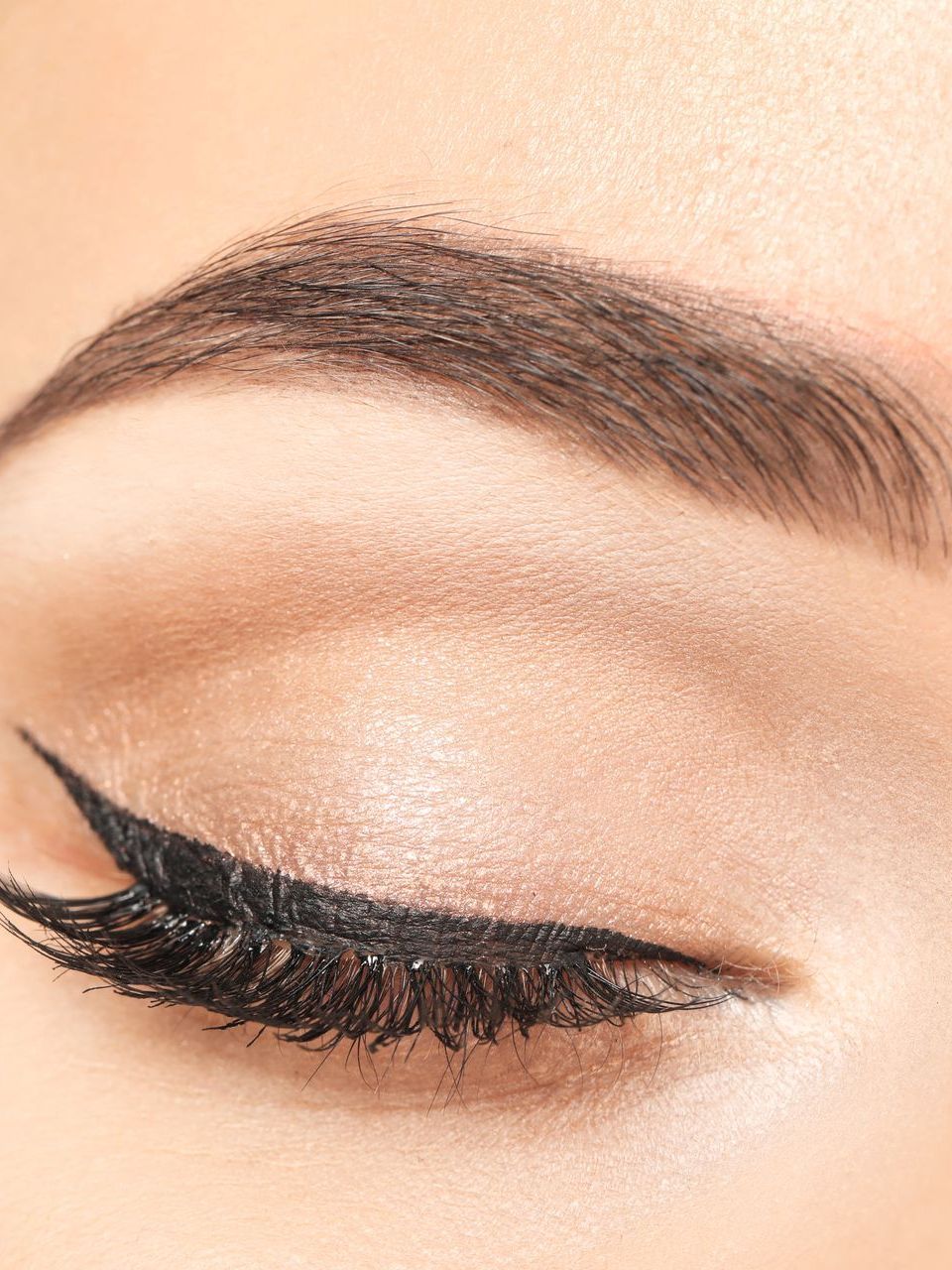 A close up of a woman 's eye with eyeliner and long eyelashes.