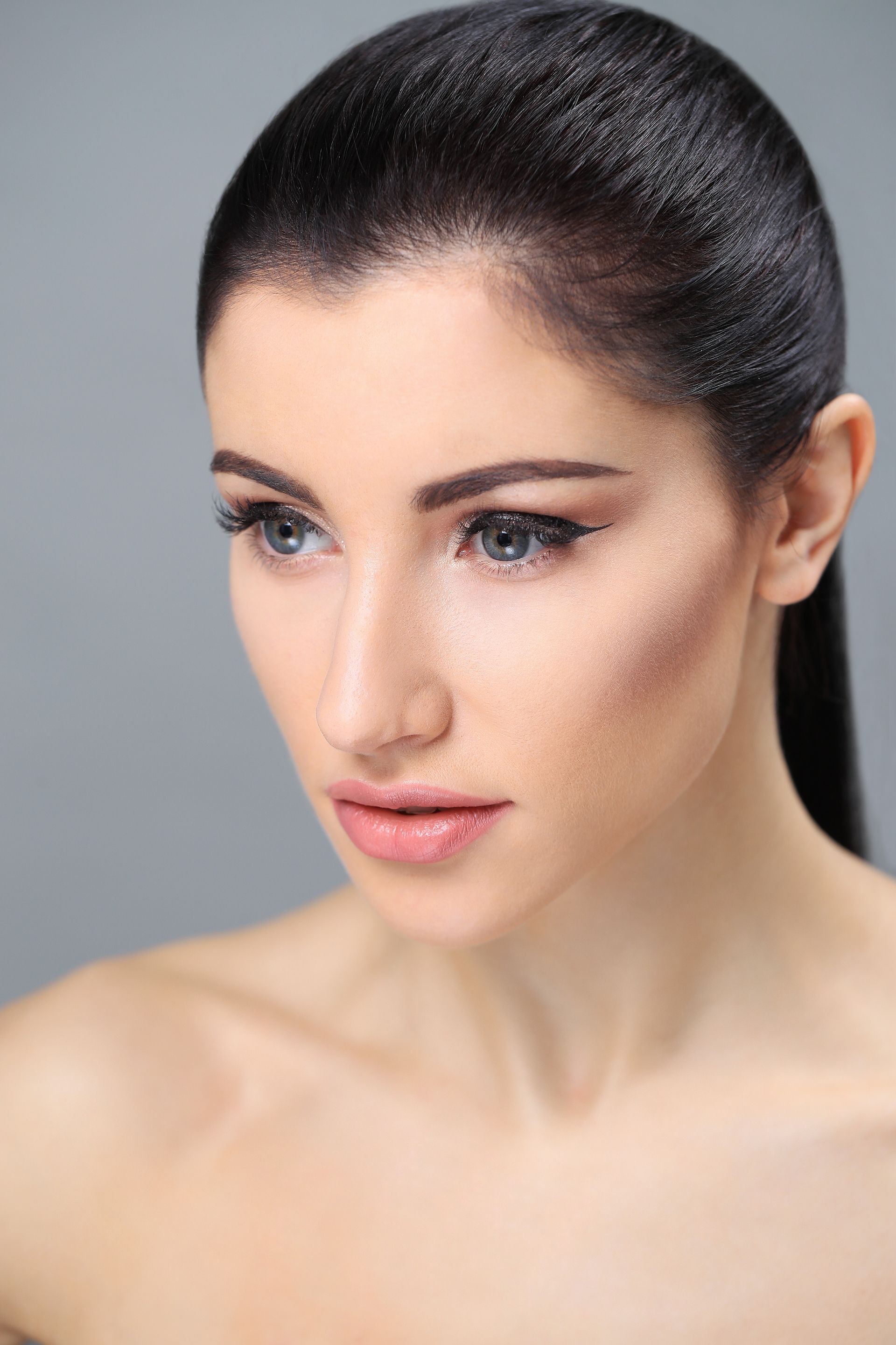 A close up of a woman 's face with a ponytail.