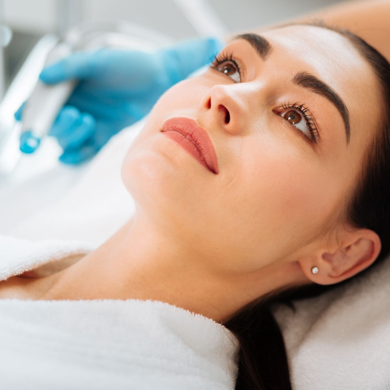 A woman is laying on a bed getting a facial treatment.