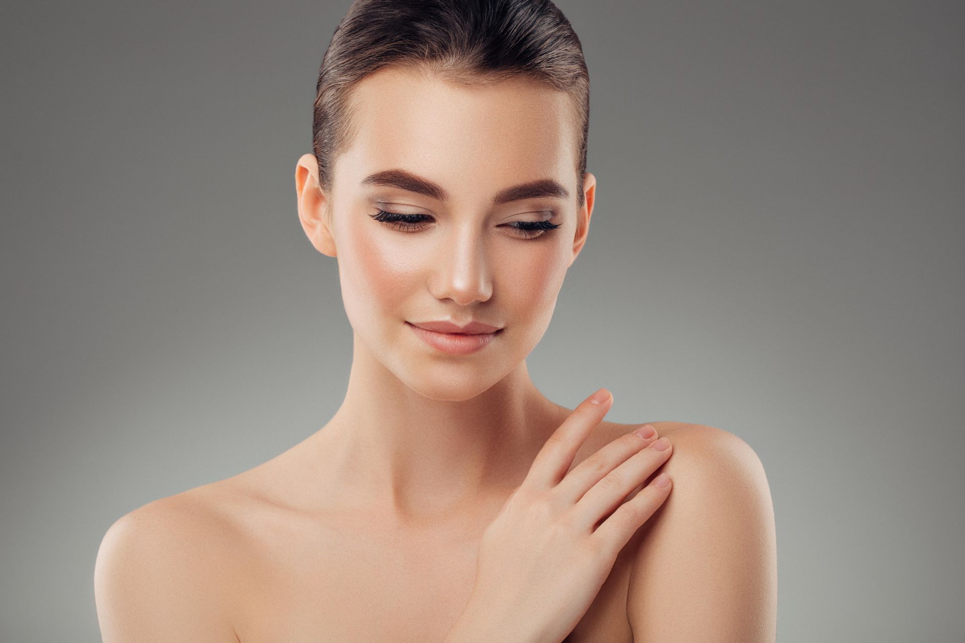 A woman is touching her shoulder with her hand.