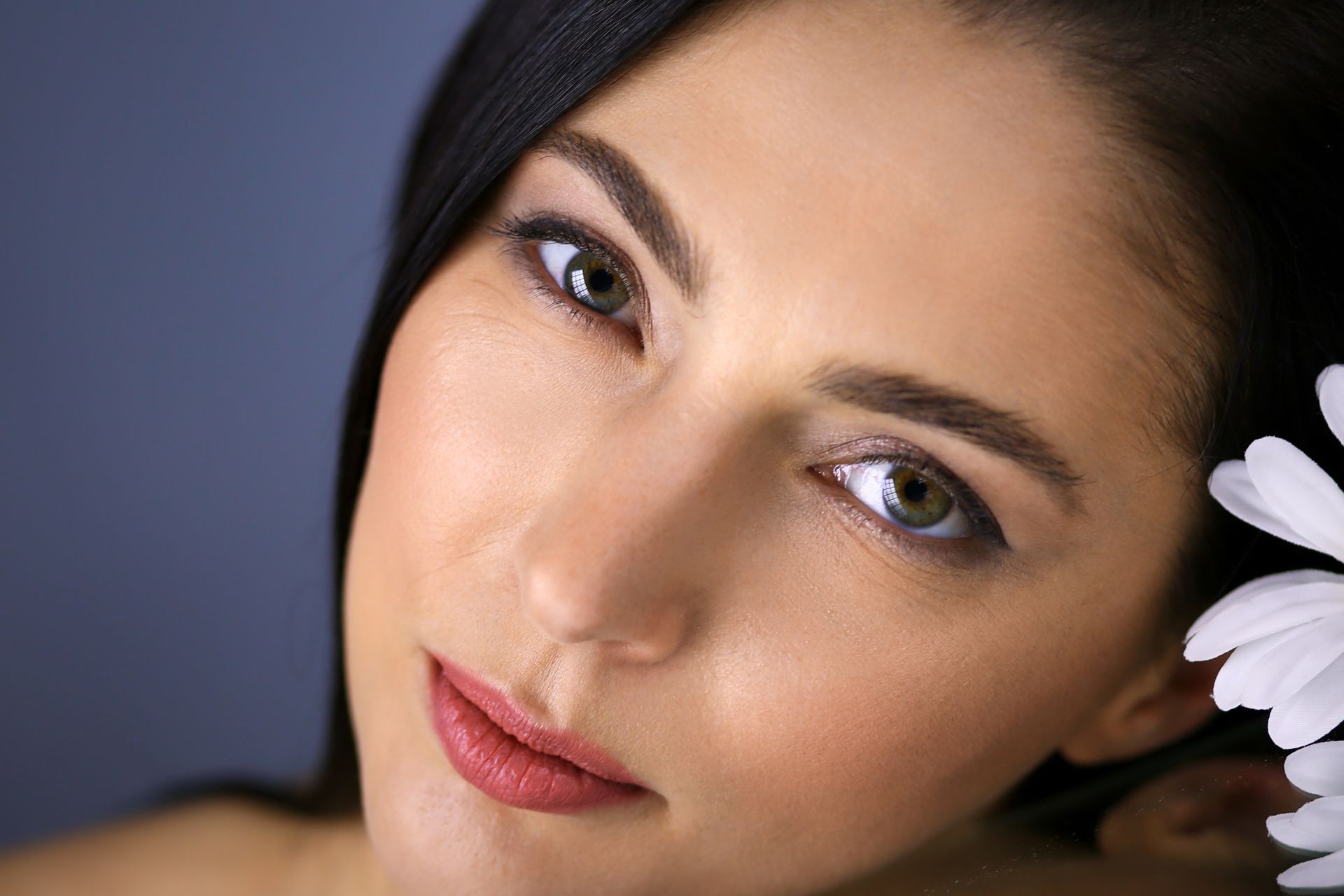 A close up of a woman 's face with a flower in her hair.