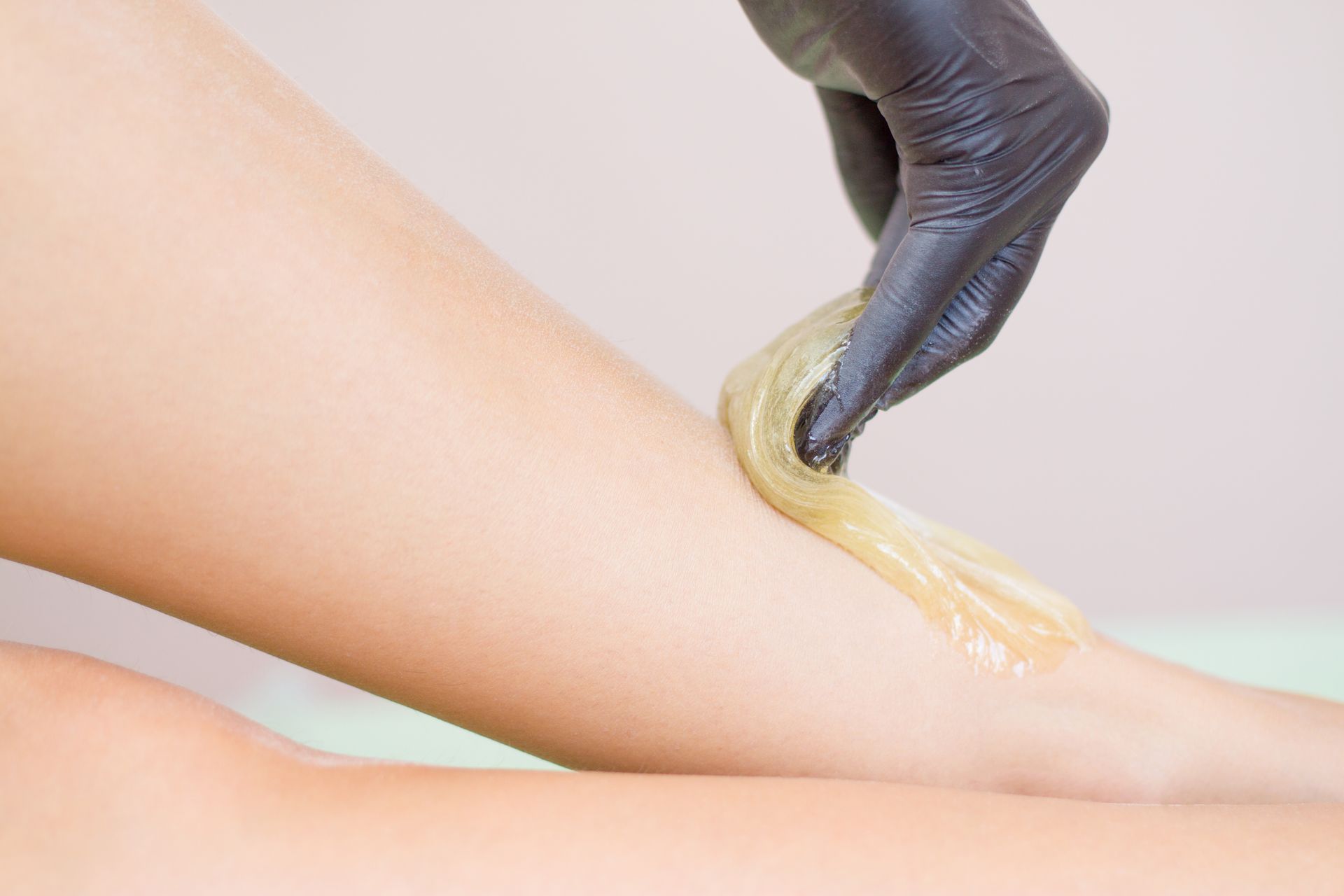 A close up of a person waxing another person 's leg.