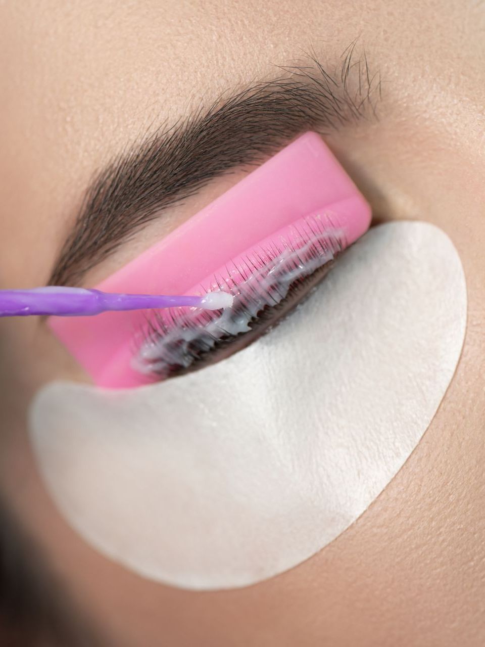 A close up of a woman 's eye with a pink brush.