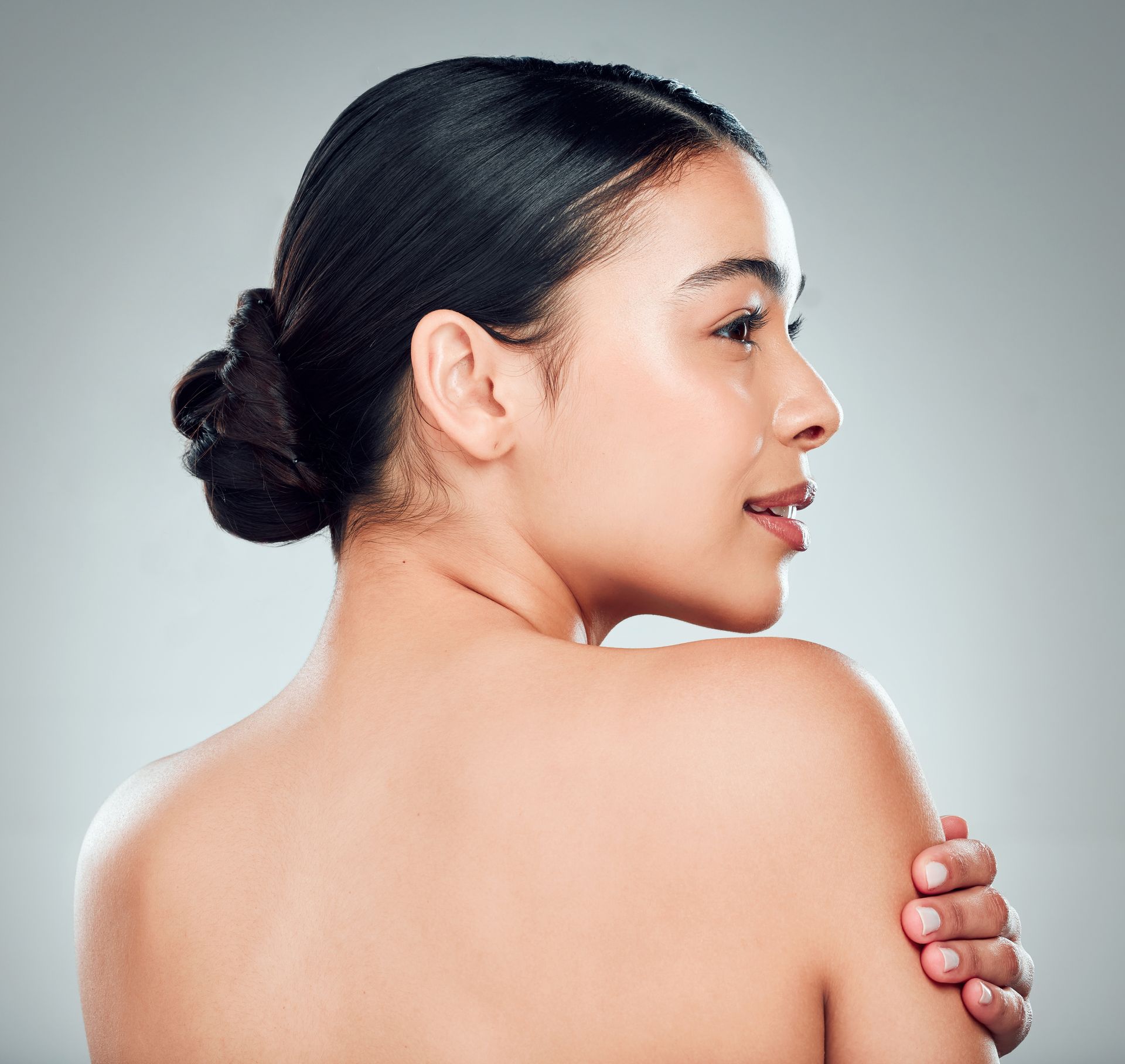 A woman without a shirt is holding her arm over her shoulder.