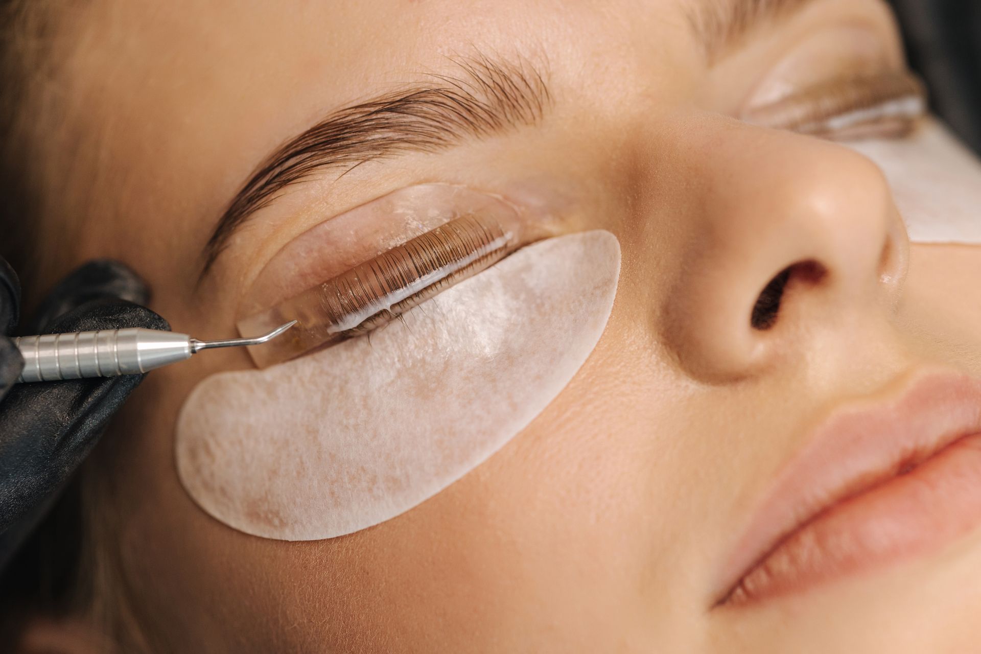 A woman is getting eyelash extensions in a beauty salon.