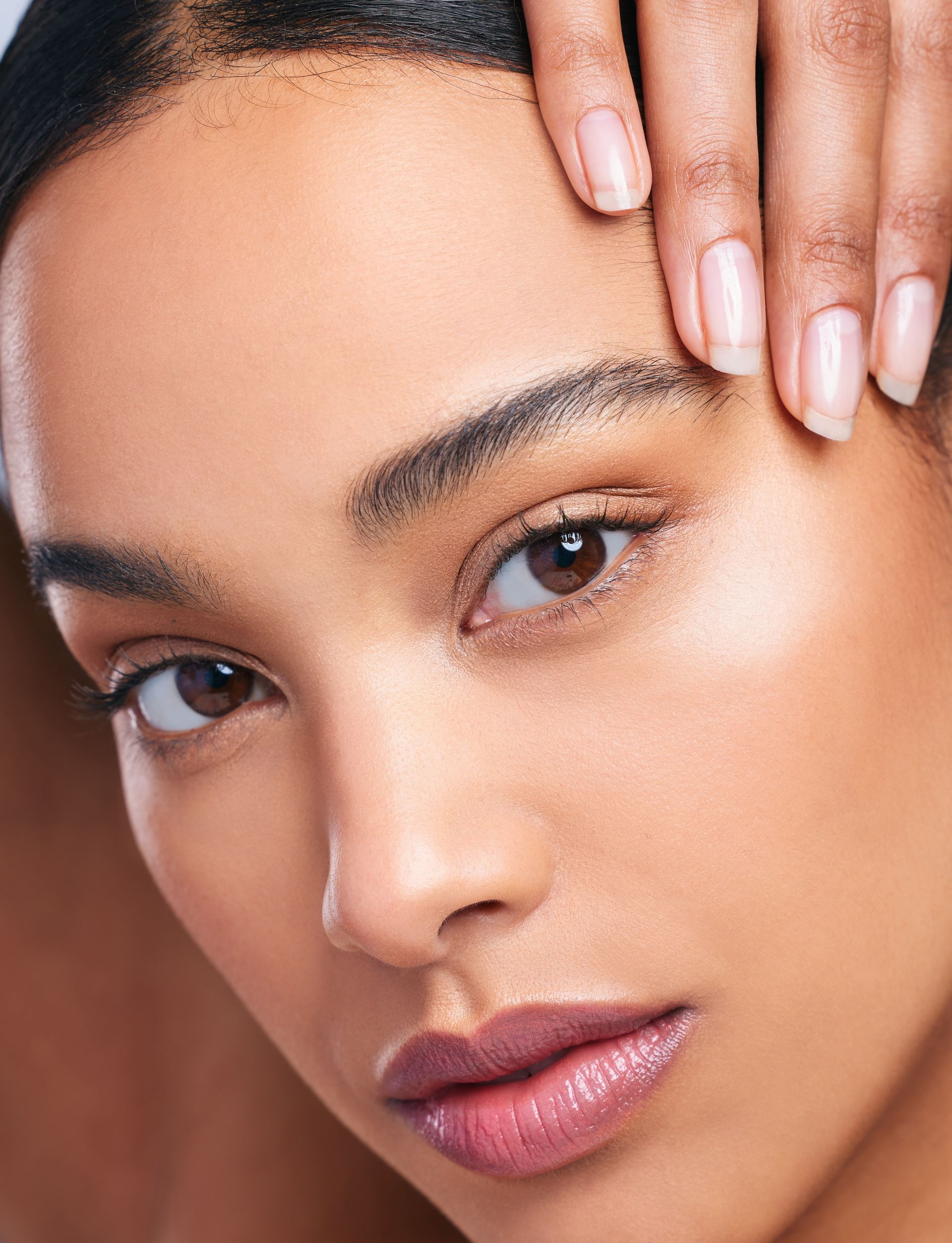 A close up of a woman 's face with her hand on her forehead.