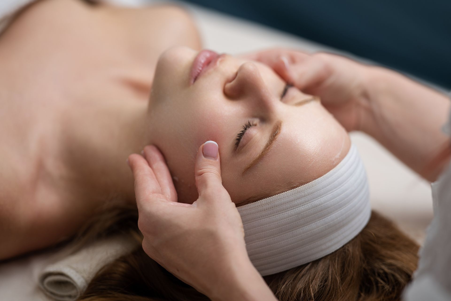 A woman is getting a facial massage at a spa.