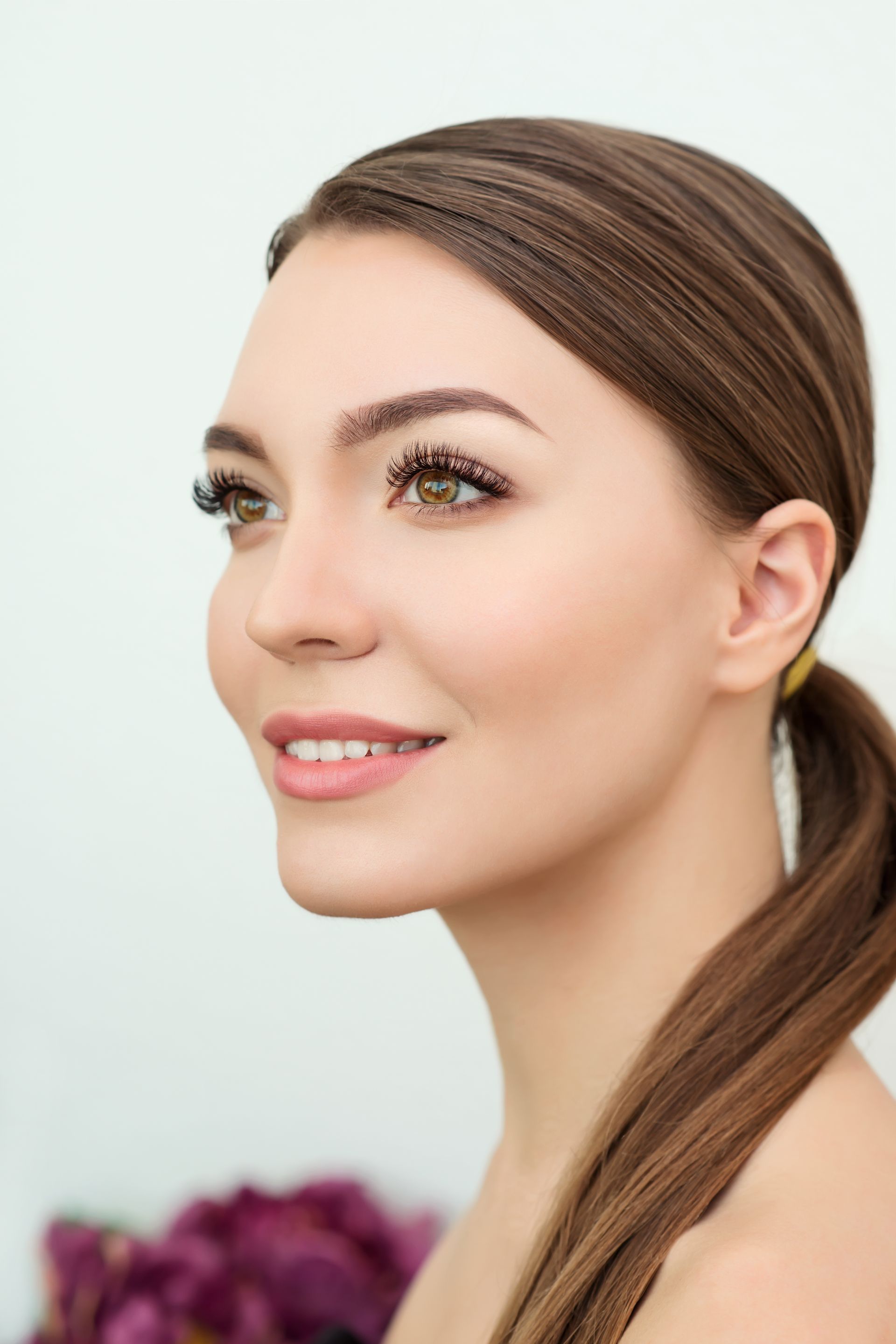 A close up of a woman 's face with long hair in a ponytail.