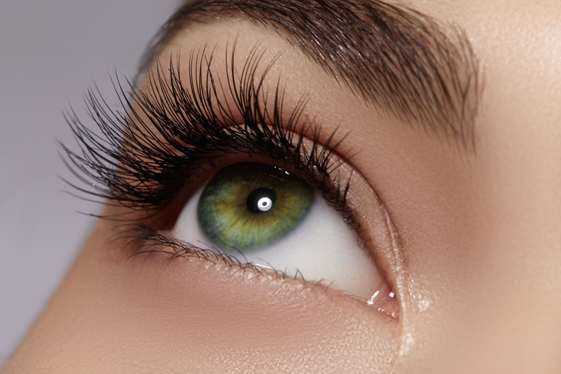 A close up of a woman 's green eye with long eyelashes.