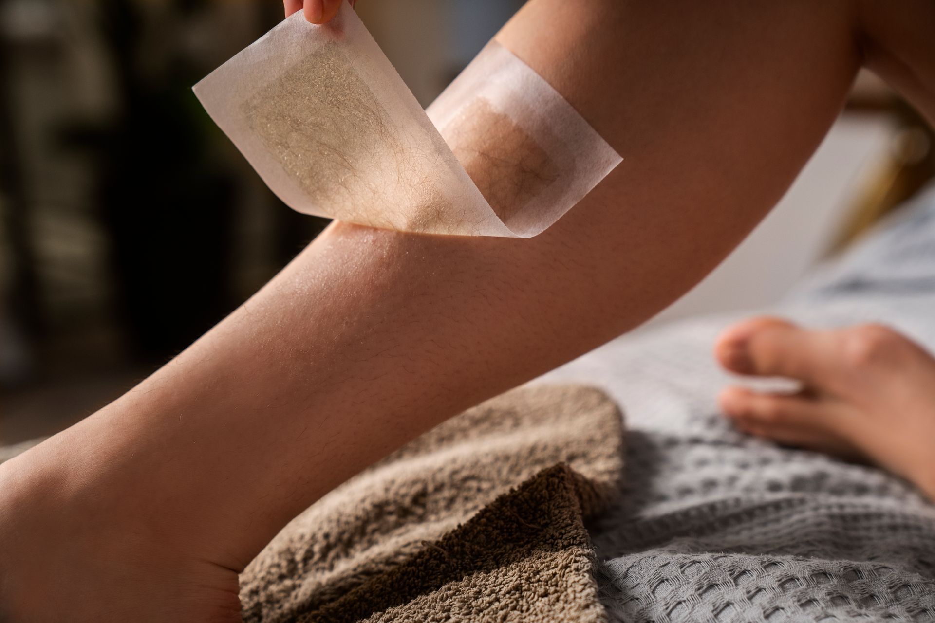 A person is waxing their leg with wax paper.