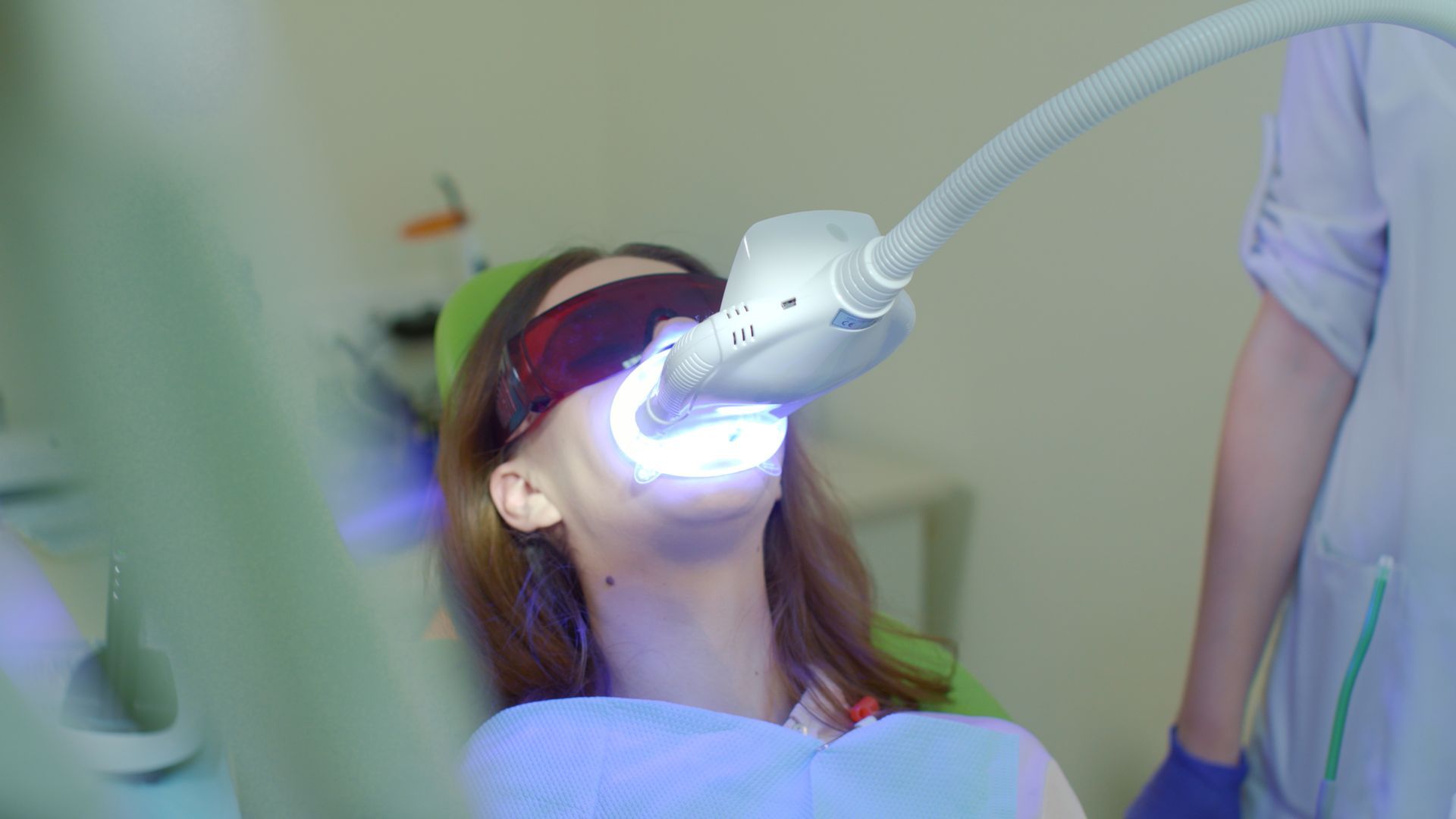 A woman is getting her teeth whitened in a dental office.