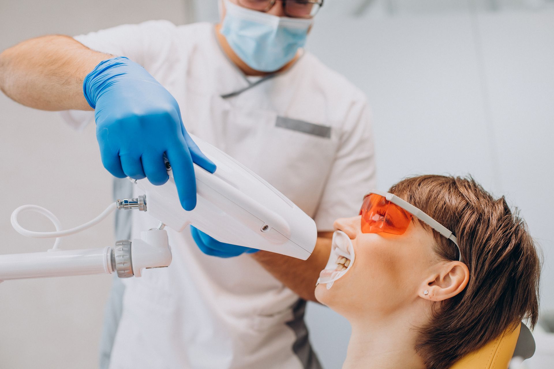 A woman is getting her teeth whitened by a dentist.