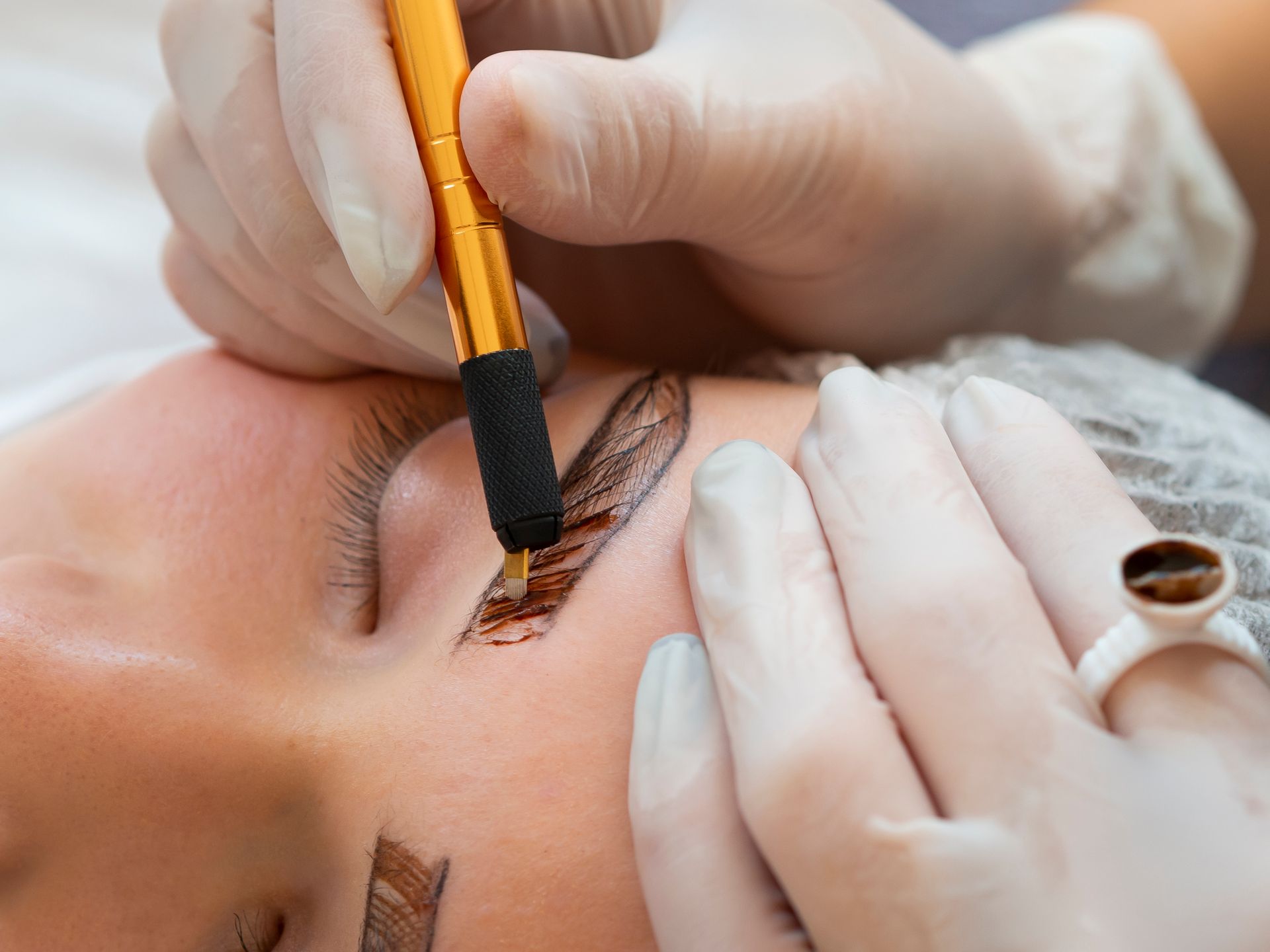 A woman is getting permanent makeup on her eyebrows.