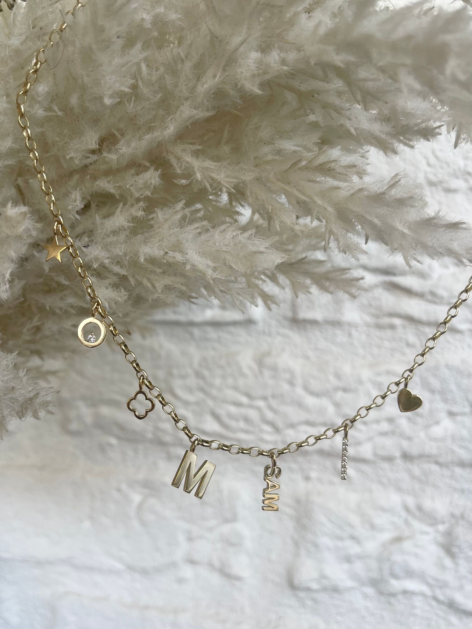 Gouden ketting met bedels, waaronder een hart, de letter 