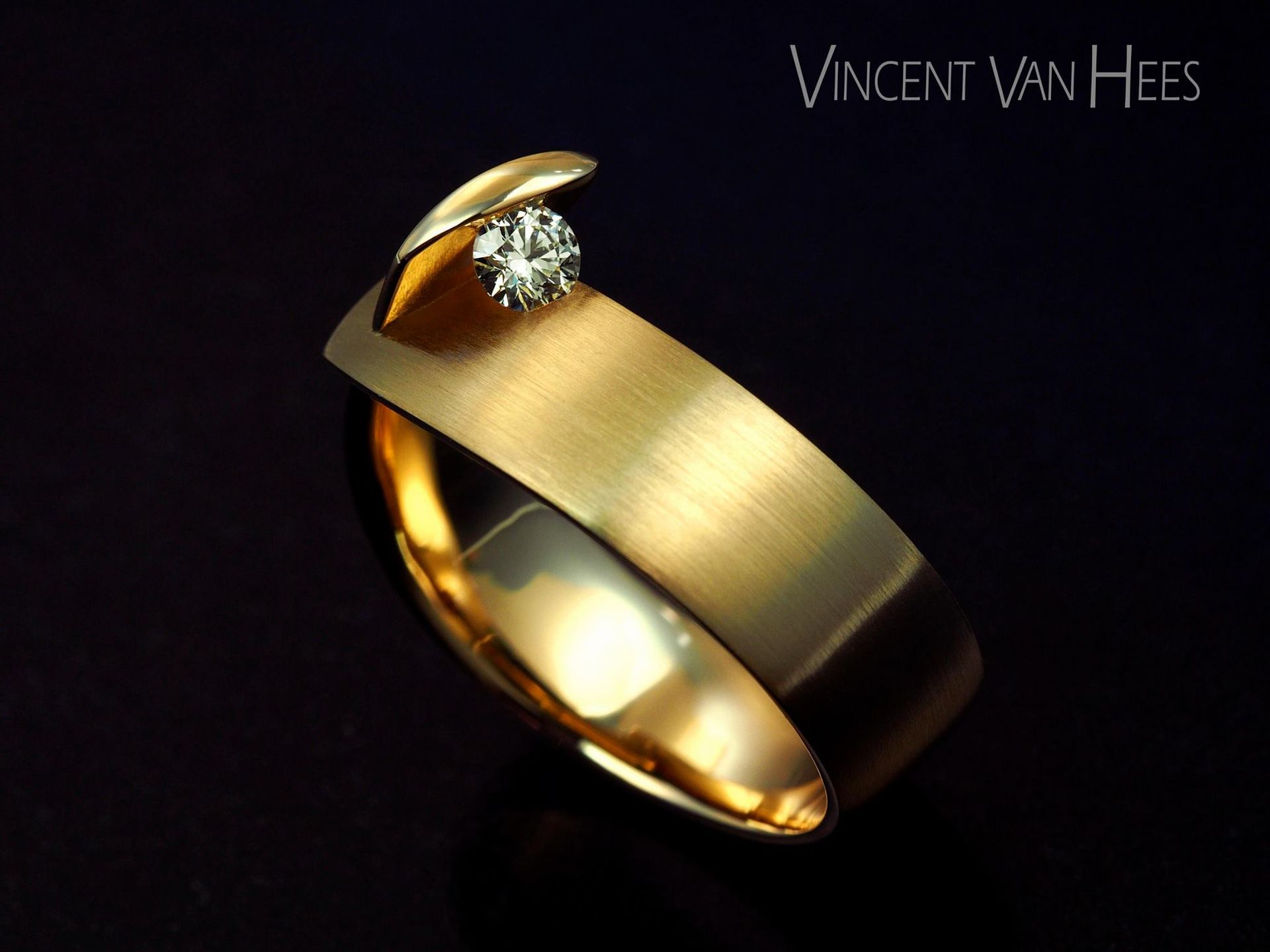 Gouden ring met een diamant in een gebogen design, op een donkere achtergrond.