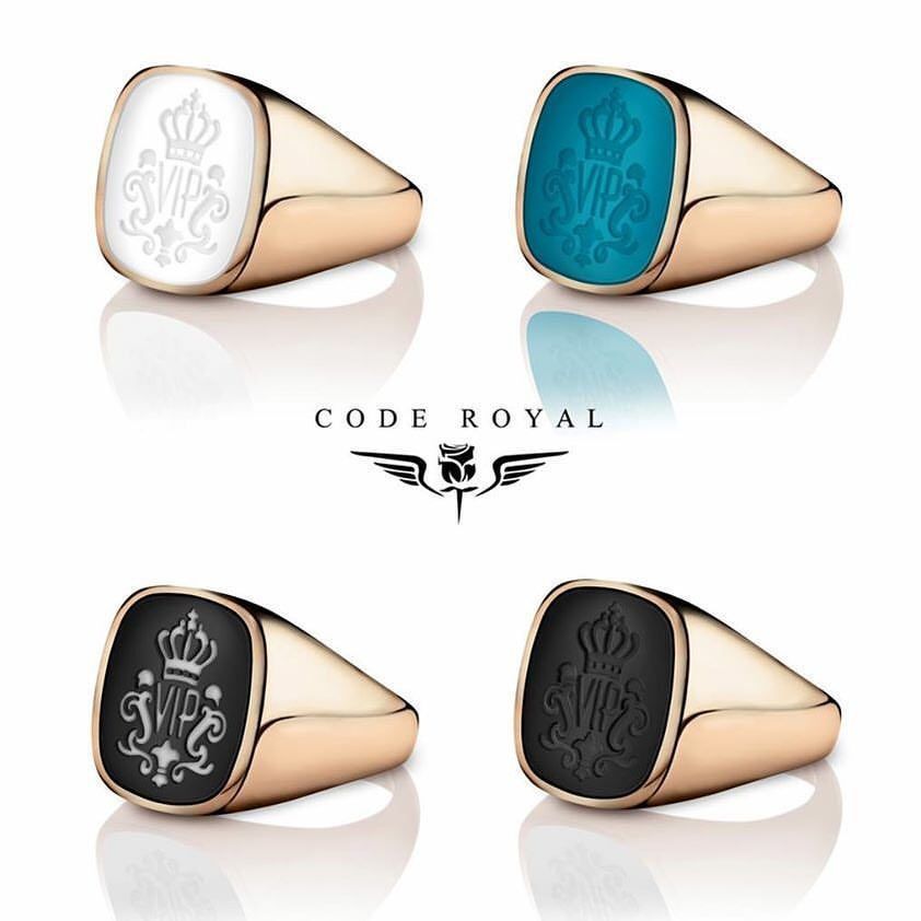 Vier zegelringen van roségoud met in het midden verschillende gekleurde stenen, elk met een kroontje en initialen.