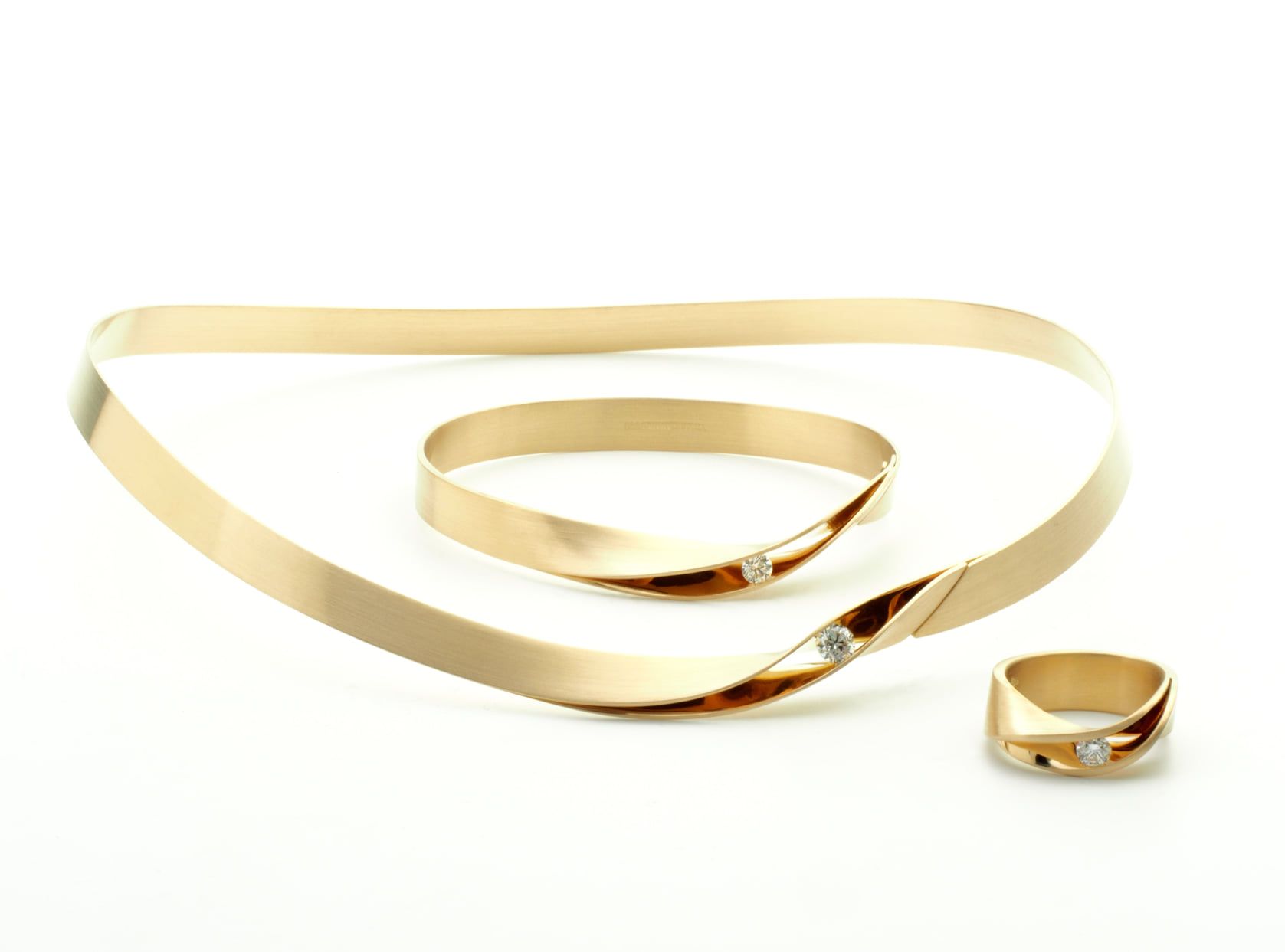 Gouden sieradenset met diamanten accenten op een witte ondergrond: ketting, armband en ring.