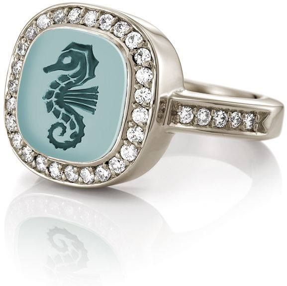 Zilveren ring met een vierkante turquoise steen met een zeepaardjemotief, omringd door diamanten.