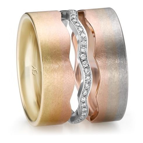Trouwringset met drie ringen: gouden, roségouden en zilveren banden met een golvende diamanten band in het midden.
