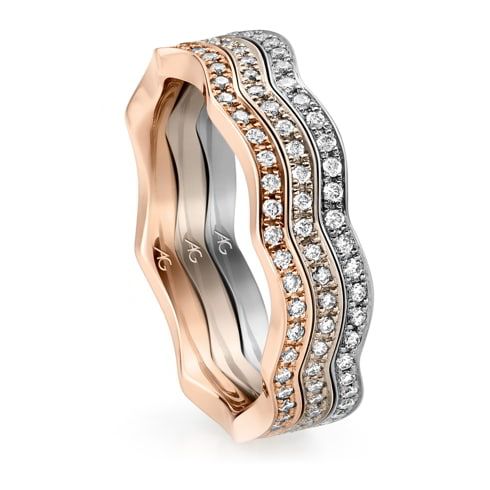 Drie golvende, stapelbare ringen: roségoud, zilver en met diamanten bezet witgoud.