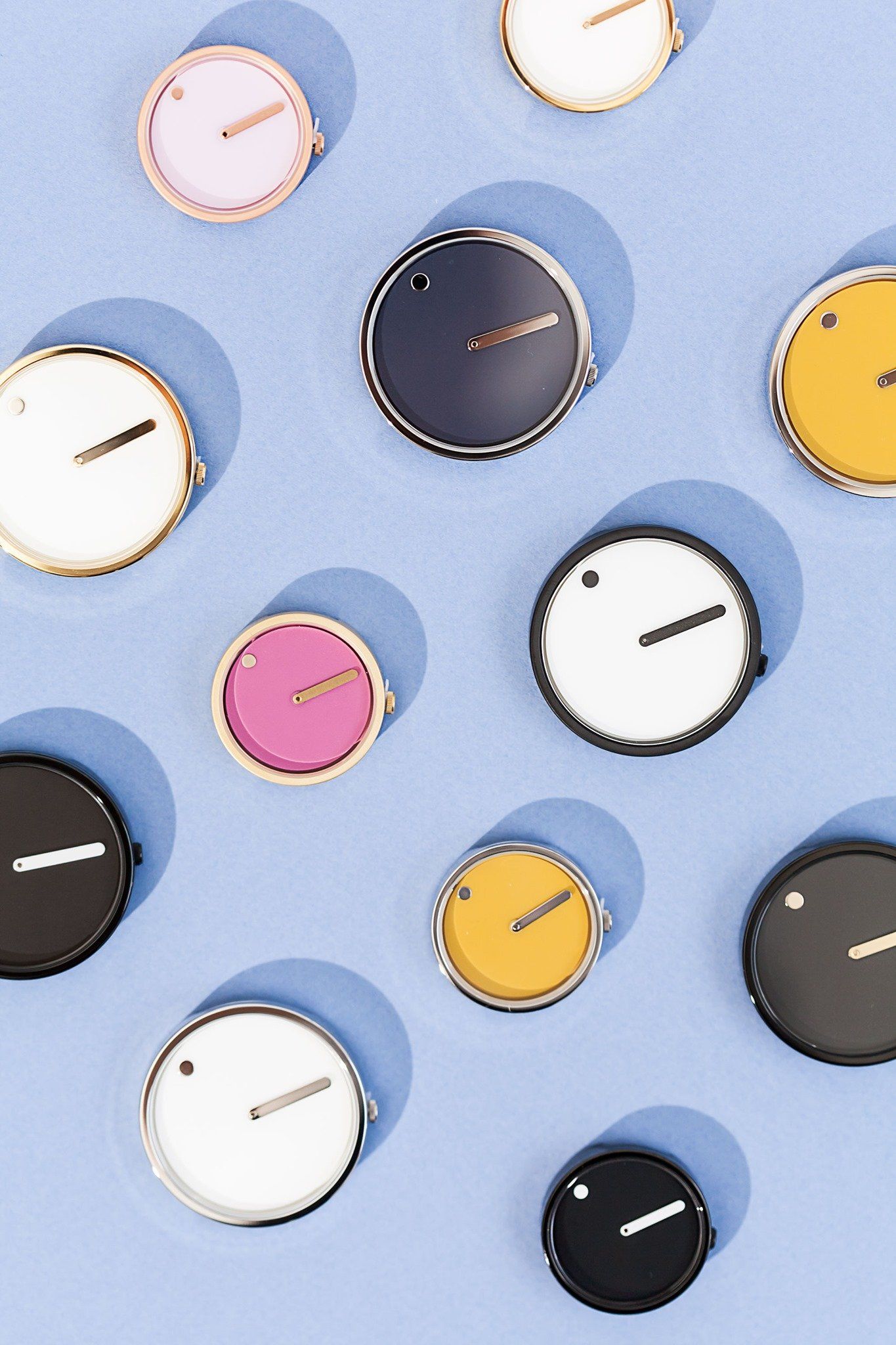 Kleurrijke horloges op een blauwe achtergrond; de wijzers geven verschillende tijden aan.