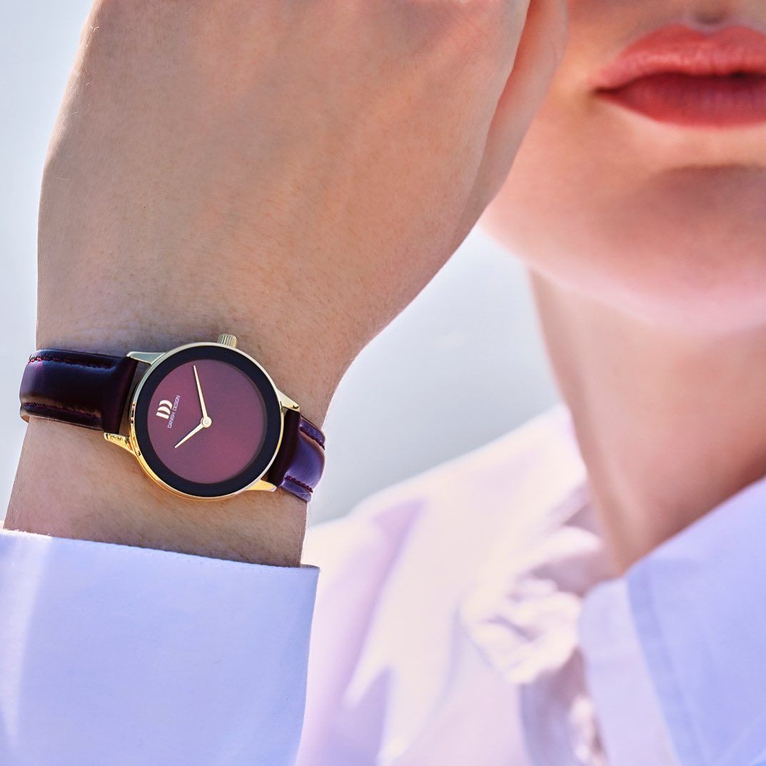 Dameshorloge met gouden montuur, kastanjebruine wijzerplaat en leren band.