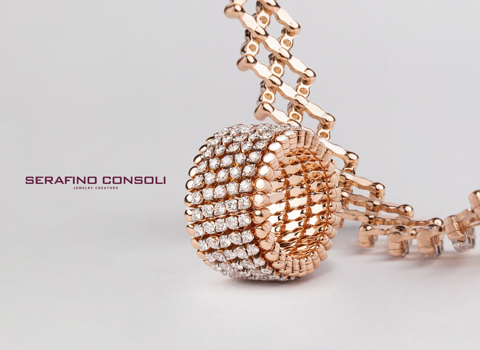 Roségouden sieraad met een met diamanten bezette bal en geometrische ketting op een witte achtergrond.