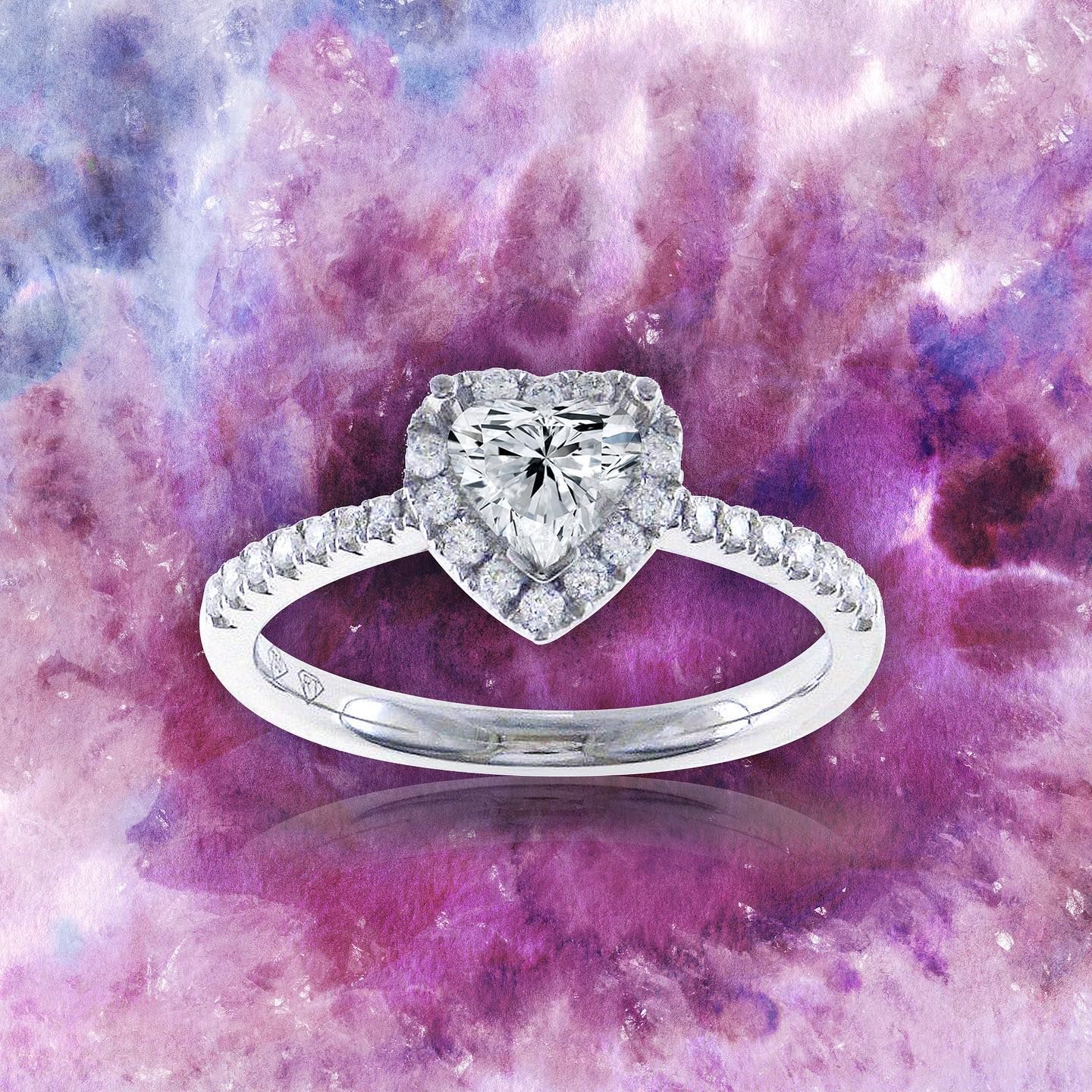 Hartvormige diamanten ring met een halo van kleinere diamanten, gezet op een met diamanten bezette band tegen een kleurrijke achtergrond.