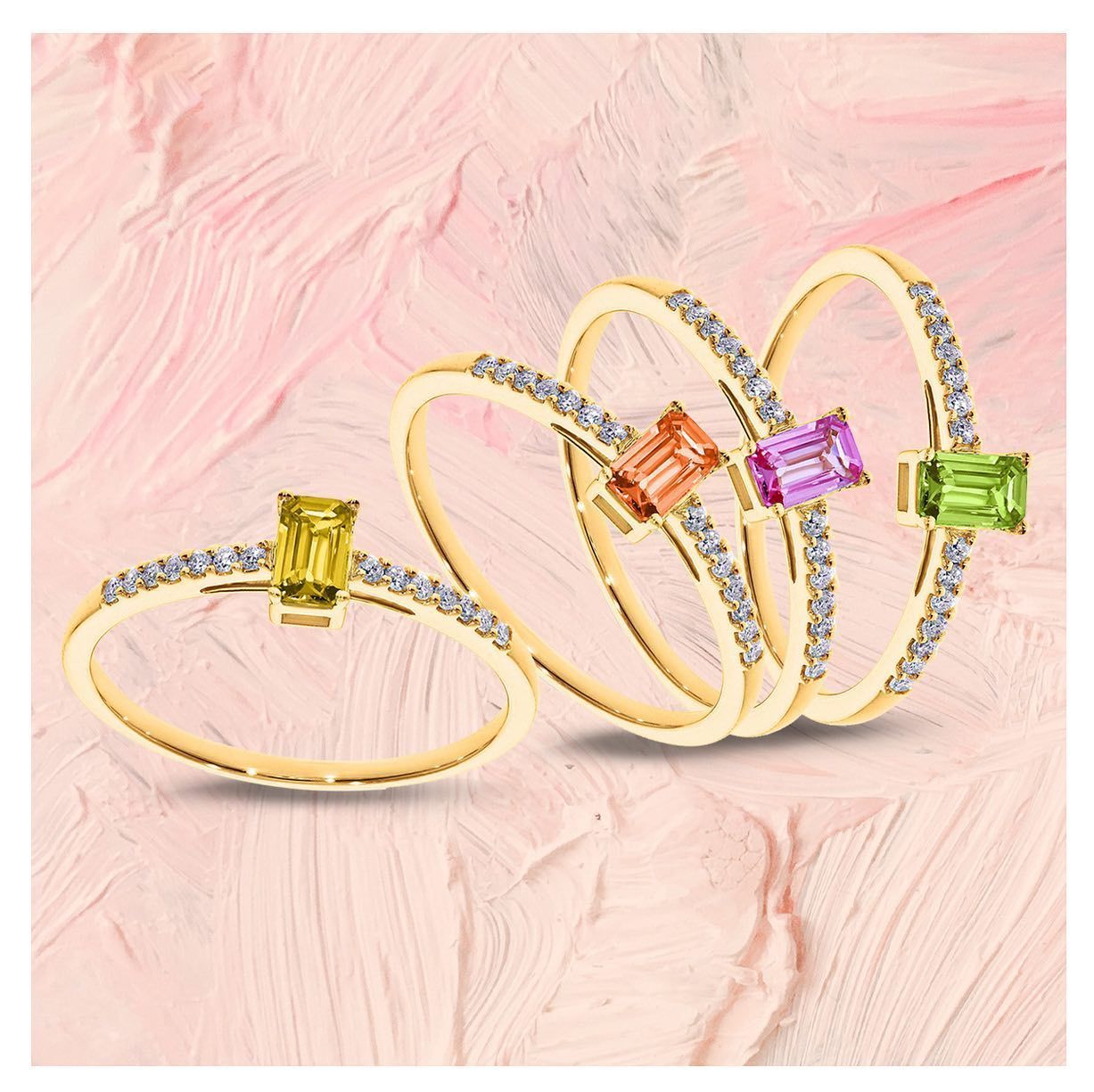 Vier gouden ringen met kleurrijke vierkante edelstenen en kleine diamanten, op een roze achtergrond.