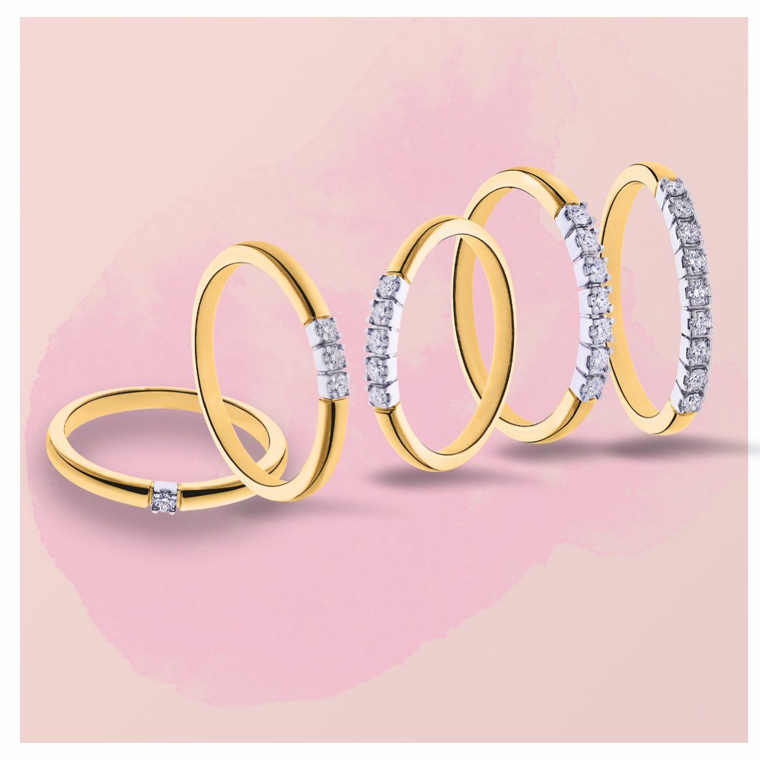 Gouden ringen met diamanten in verschillende patronen op een roze achtergrond.