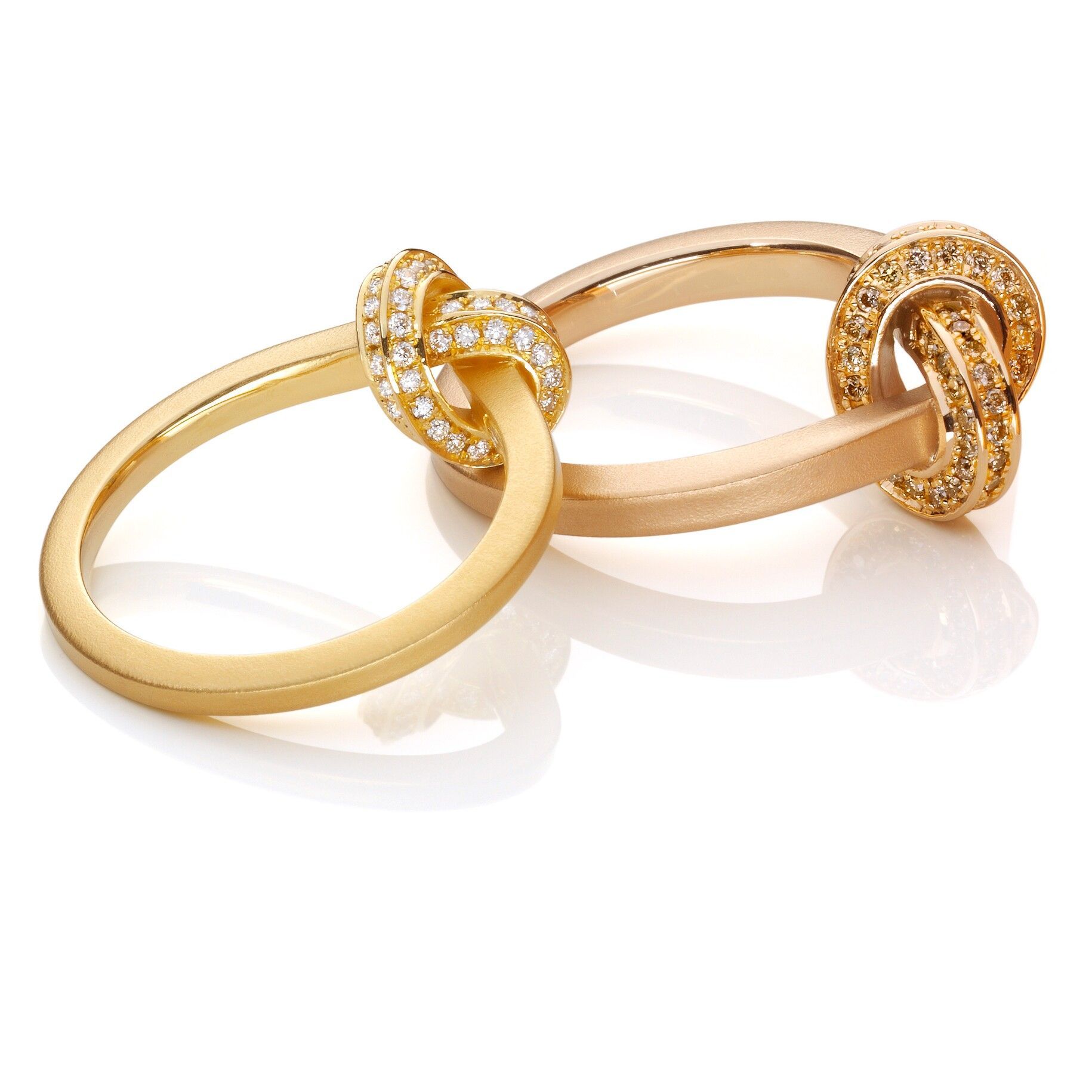 Twee in elkaar grijpende gouden ringen, waarvan één met diamanten.