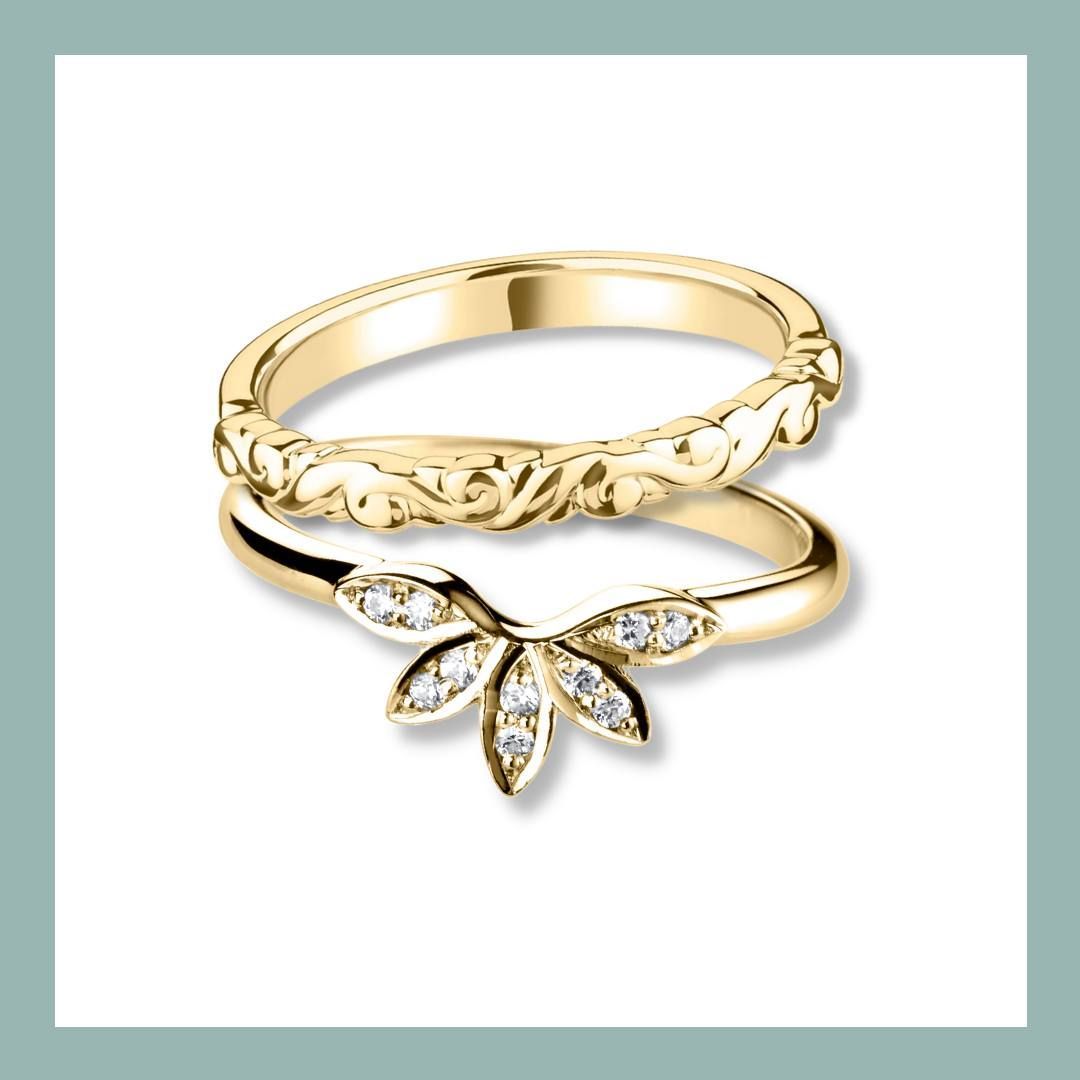 Twee gouden trouwringen, één met bloemmotief en de andere met diamanten bladeren.