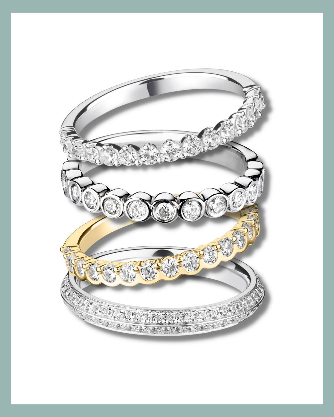 Vier op elkaar gestapelde diamanten ringen, met witte en gouden banden, met verschillende diamantzettingen.