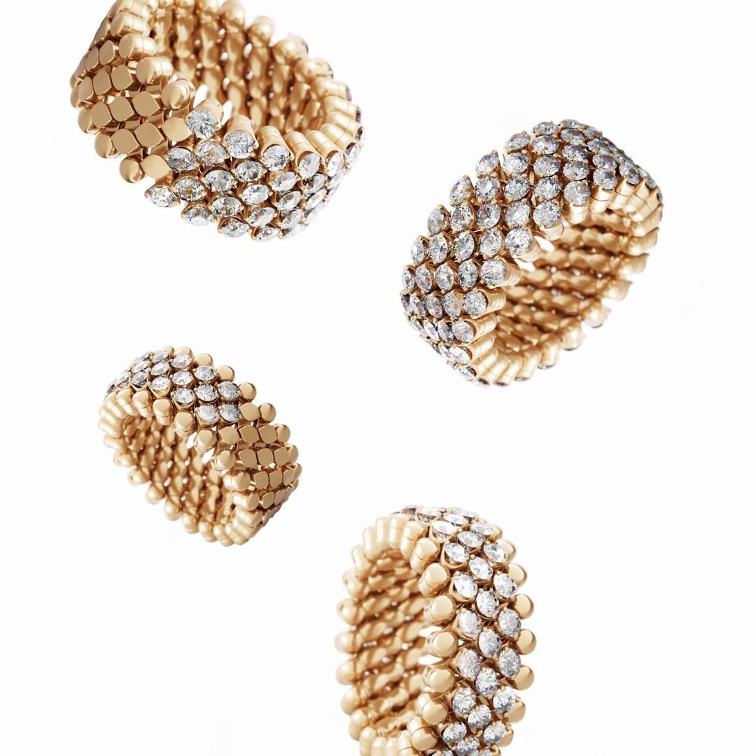 Vier gouden en diamanten ringen zweven tegen een witte achtergrond.