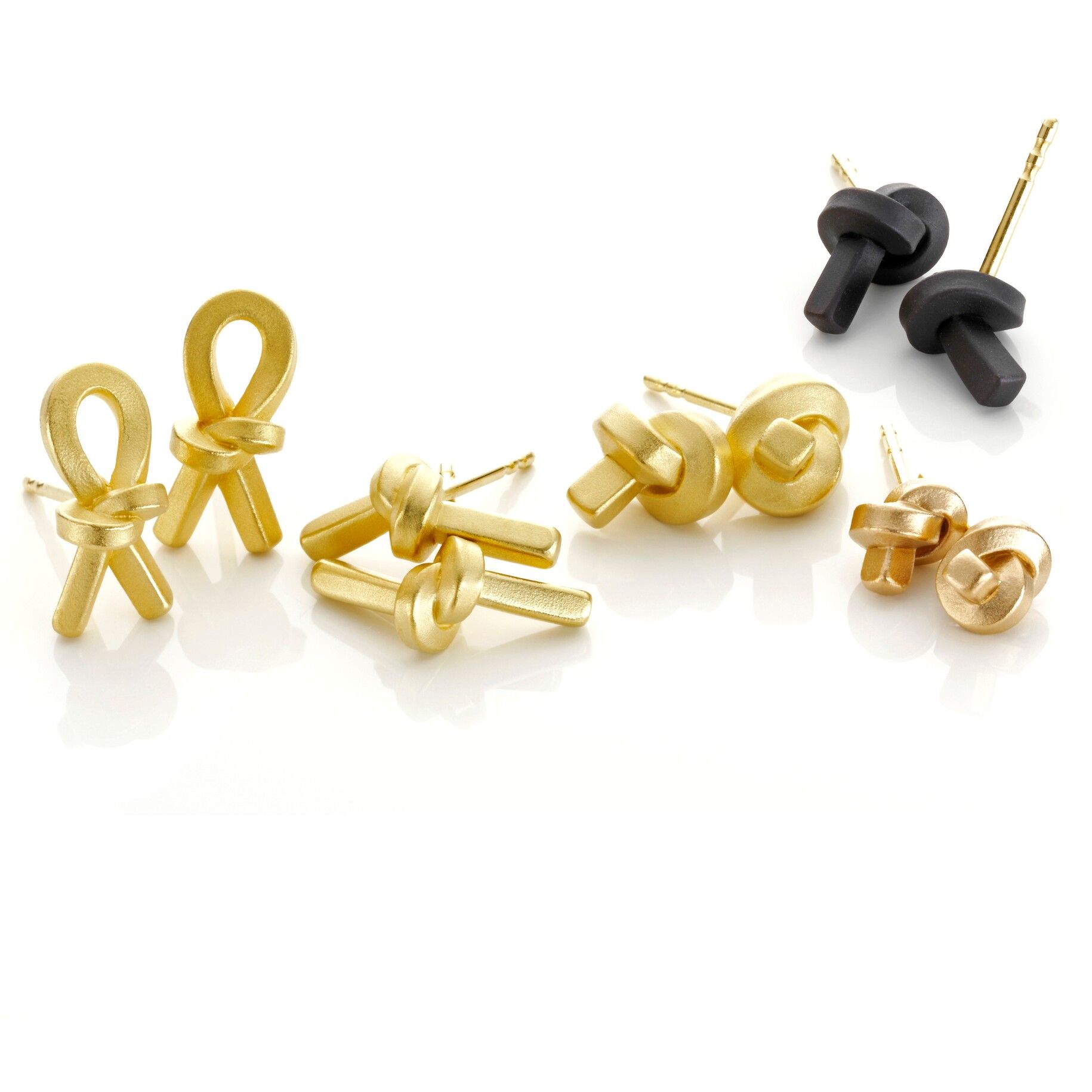 Oorbellen: Verschillende gouden en zwarte knoopvormige oorbellen op een witte achtergrond.