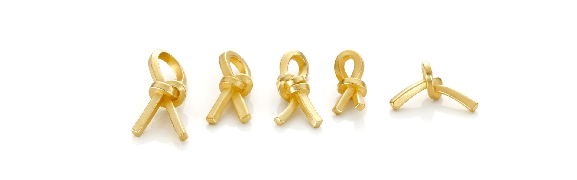 Vijf kleine gouden lintvormige ornamenten op een witte achtergrond.