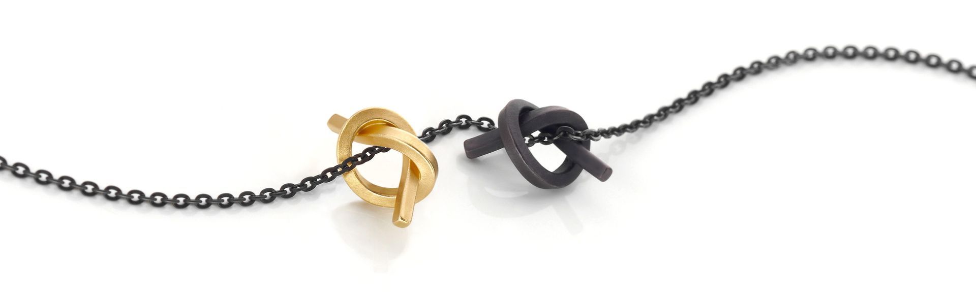 Gouden en donkere metalen knoopkettingen op een wit oppervlak.