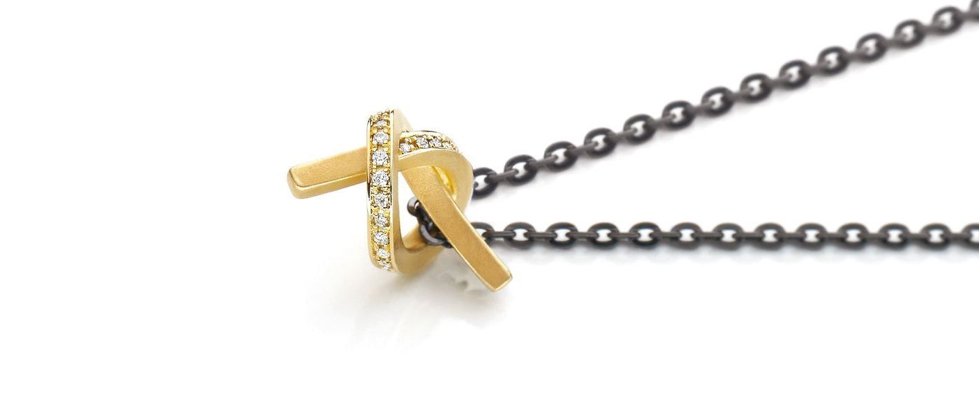 Gouden knoophanger met grijze ketting op een witte achtergrond.