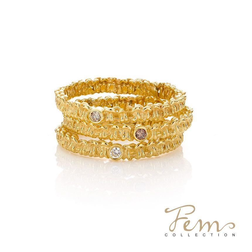 Stapel goudkleurige ringen met ingelegde edelstenen; logo van Fem Collection in de hoek.