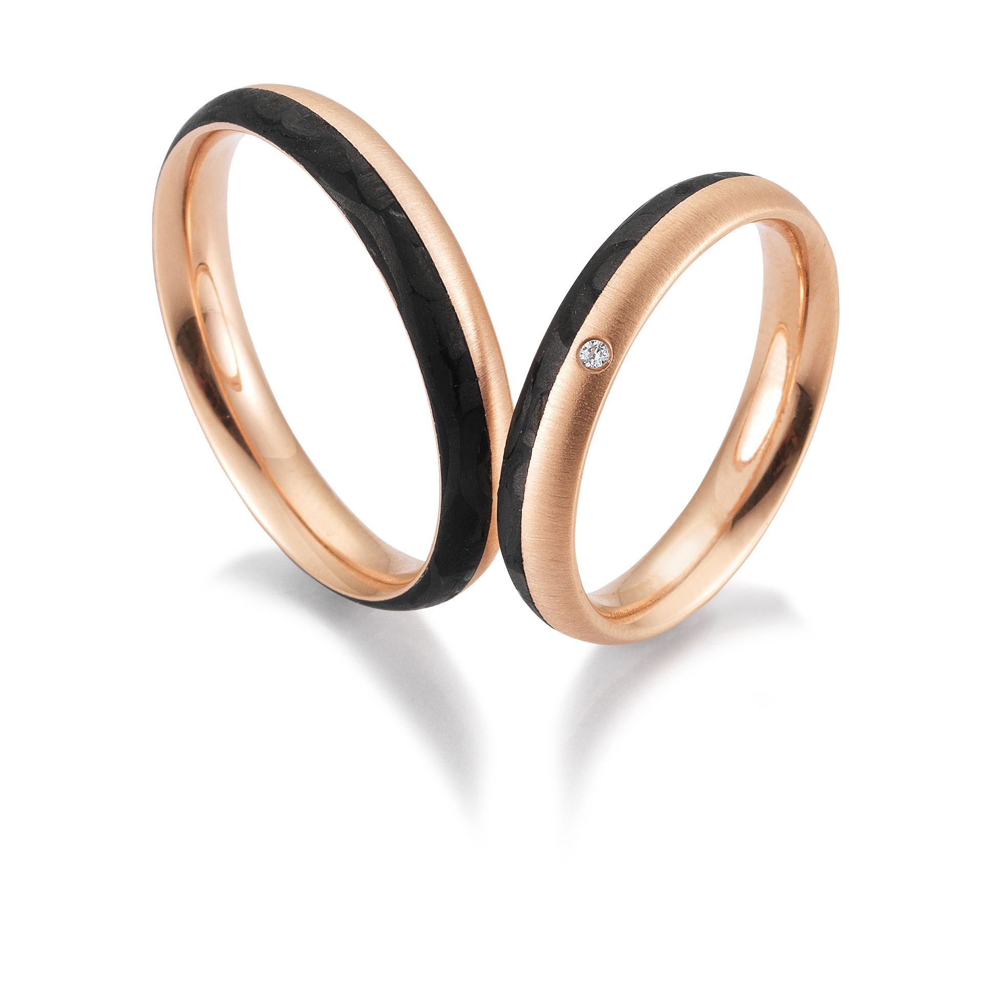Twee trouwringen van roségoud met zwarte inleg, waarvan één met een kleine diamant.