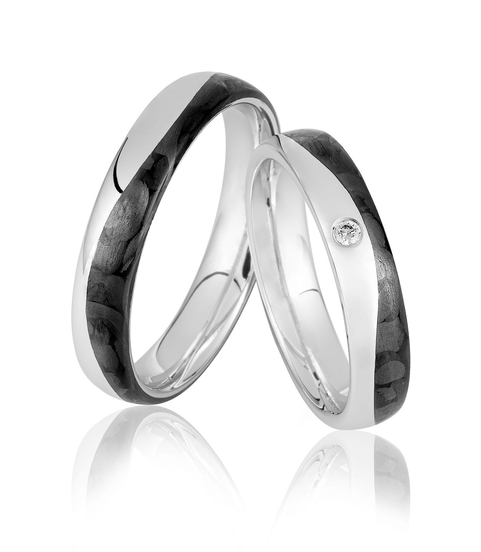 Twee trouwringen; zilveren banden met donkere, gepatroneerde inzetstukken, één met een kleine diamant.