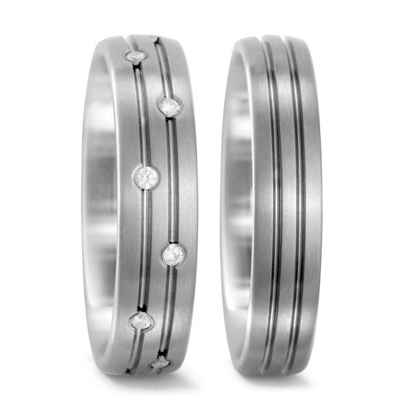 Twee zilveren trouwringen, één met diamanten en één met groeven.