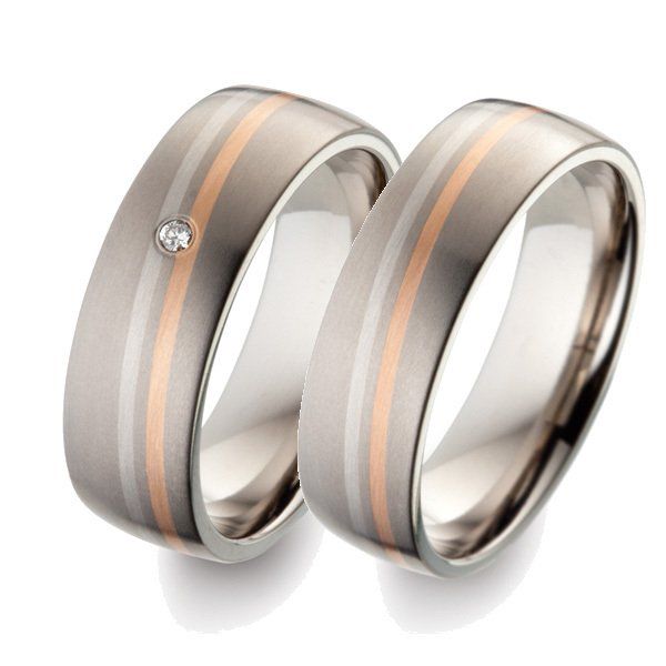 Twee trouwringen met een matte, grijze afwerking, roségouden streep en één met een diamant.