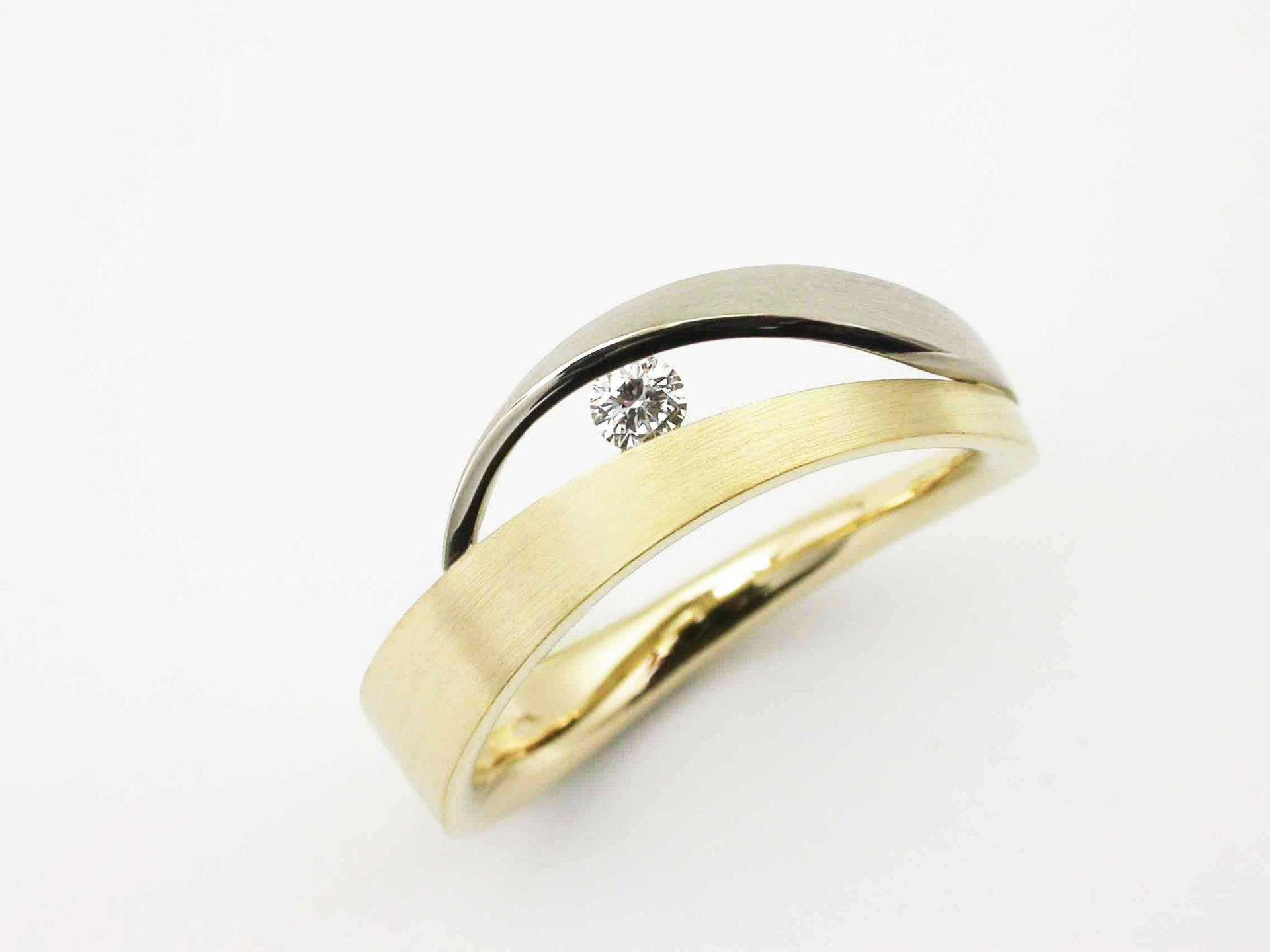Tweekleurige gouden ring met een kleine diamant op een witte achtergrond.
