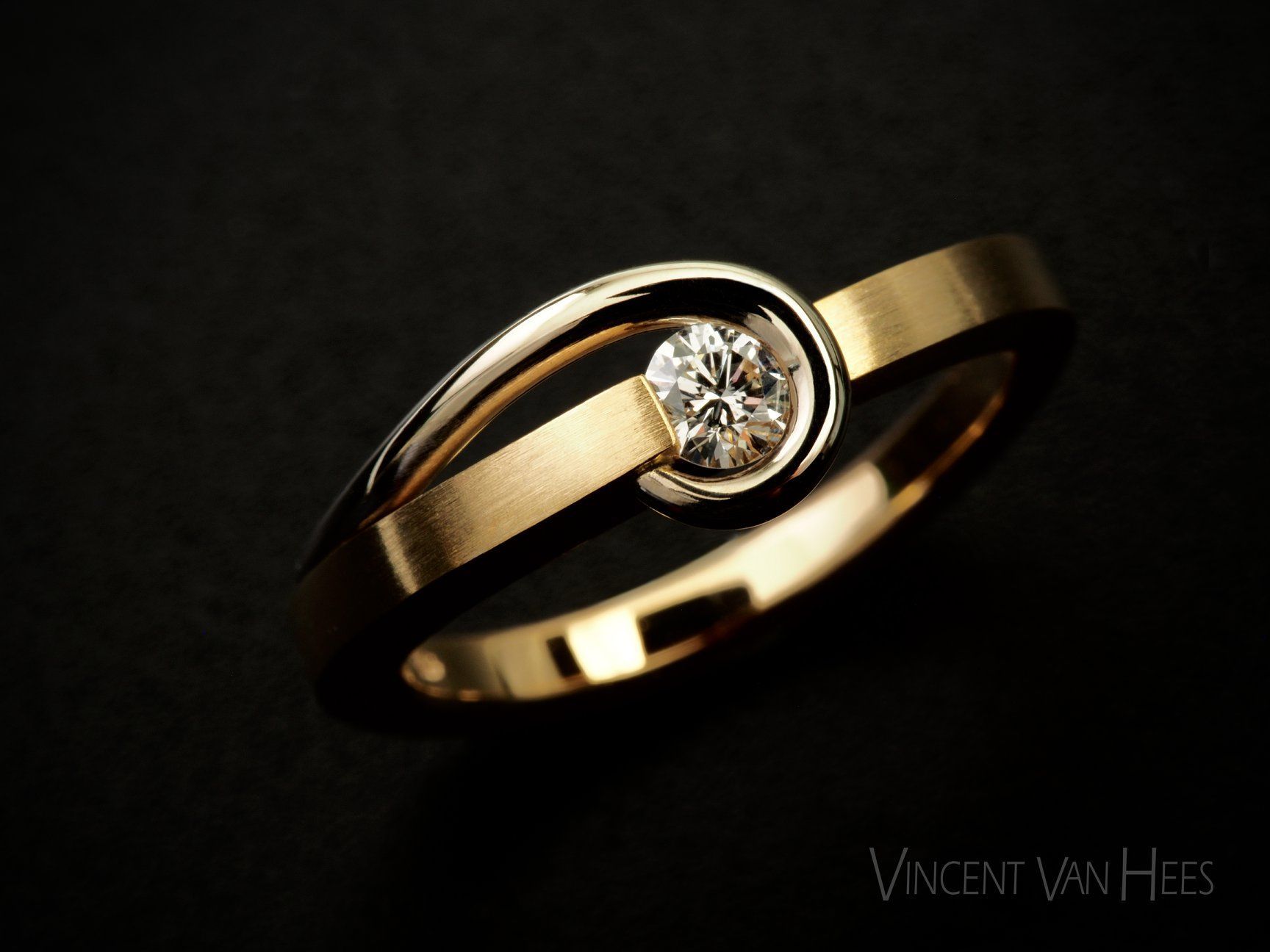 Gouden verlovingsring met een diamant in het midden van een wervelend ontwerp.