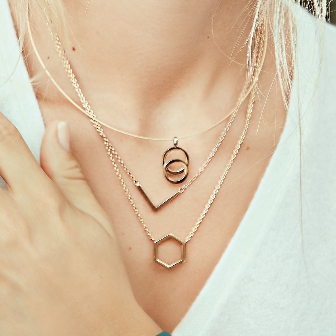 Kettingen: gouden kettingen die om de borst van een persoon worden gedragen, een wit shirt, een zeshoekige hanger.