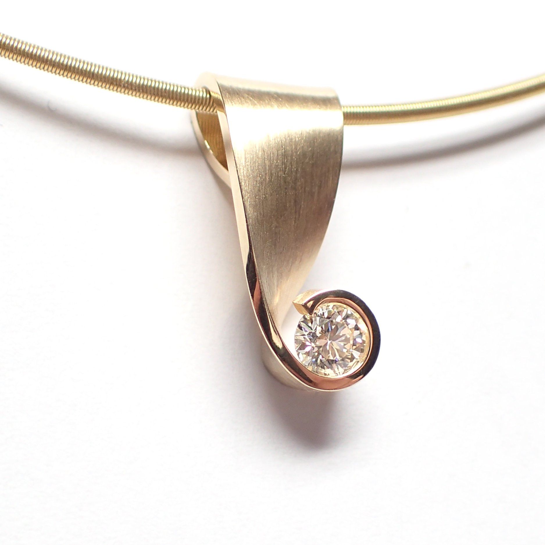 Gouden hanger met een diamant, hangend aan een dunne gouden ketting.