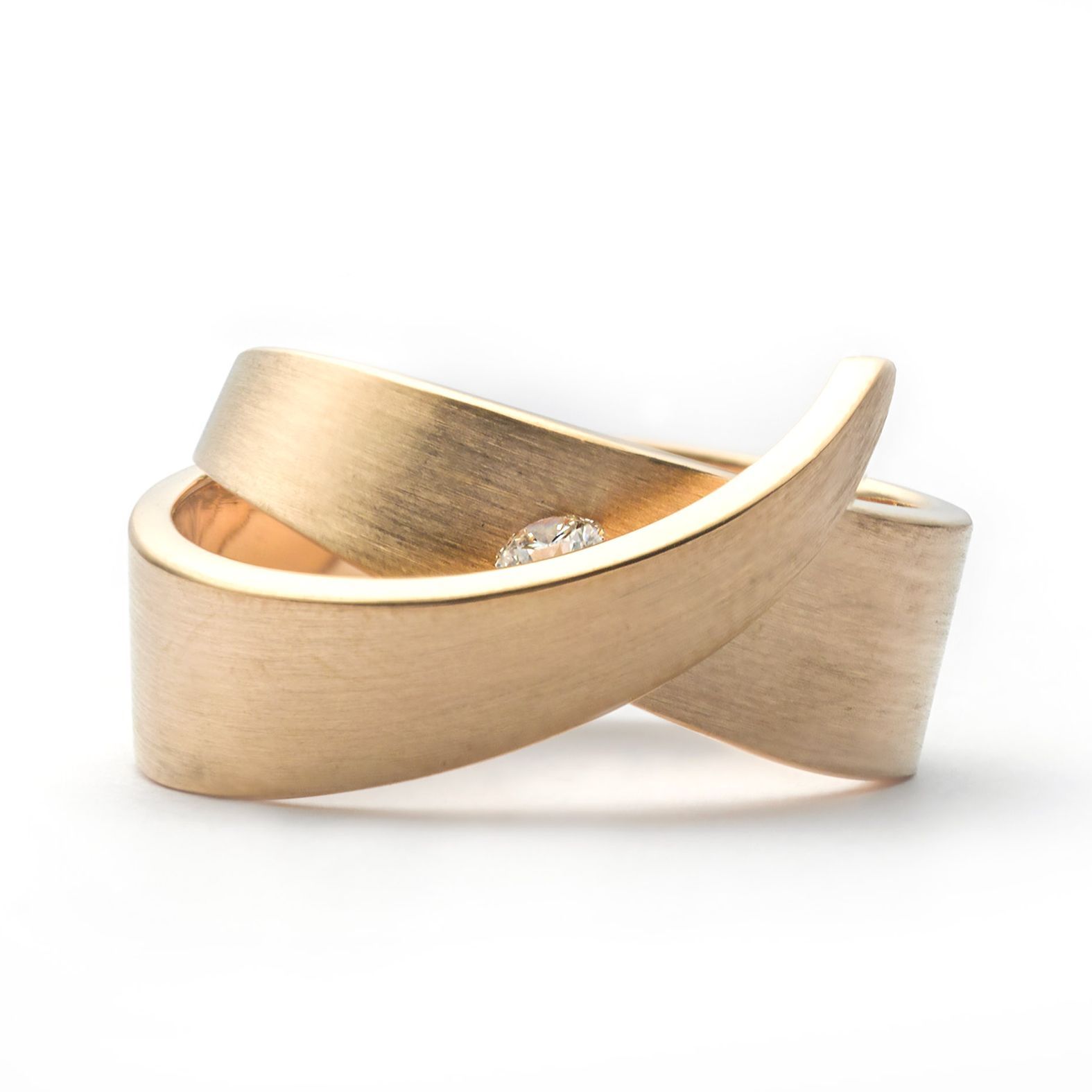 Gouden ring met een wervelend lintvormig ontwerp en een klein diamantaccent.