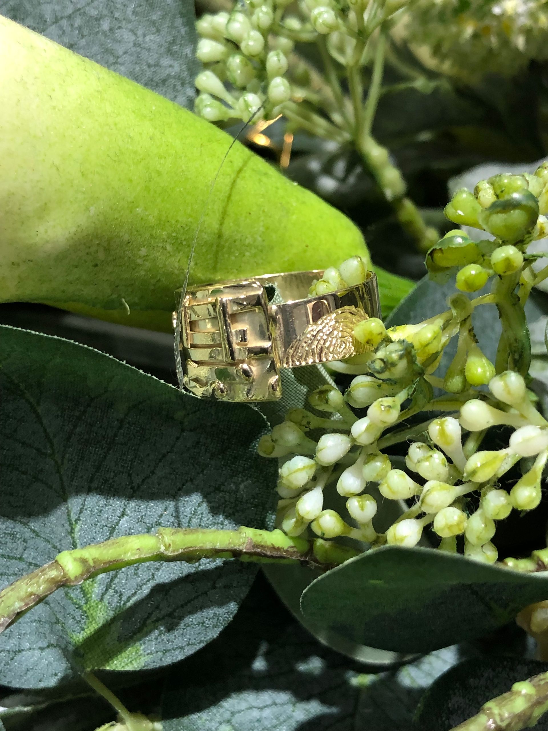 Handen die met een pincet een edelsteen in een sieradenzetting plaatsen die aan een polijstmachine is bevestigd.