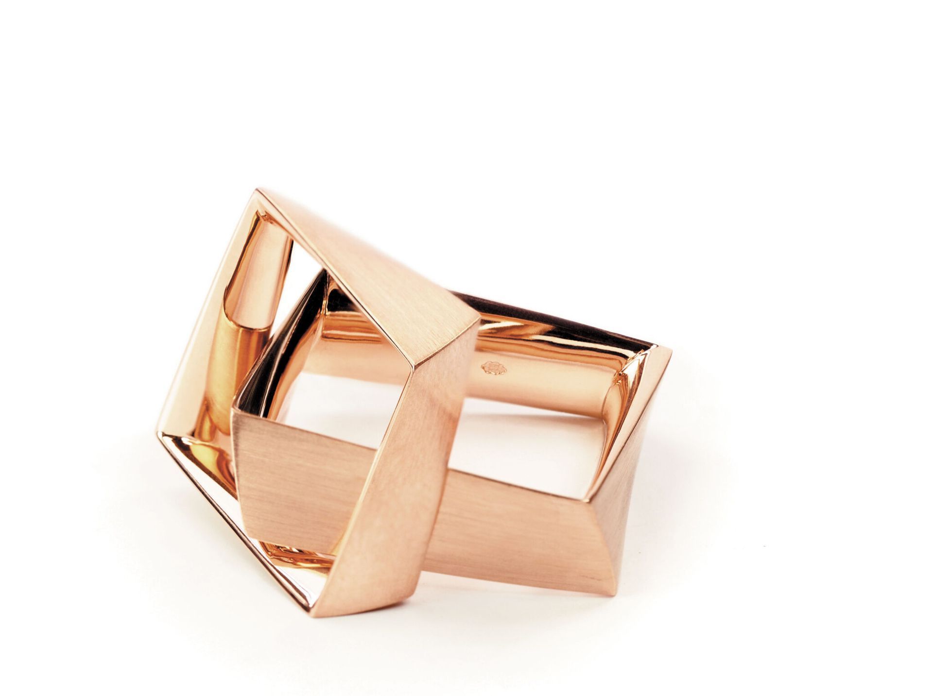 Hand in de zak van een grijze visgraatrok, met een grote ring in haar hand.